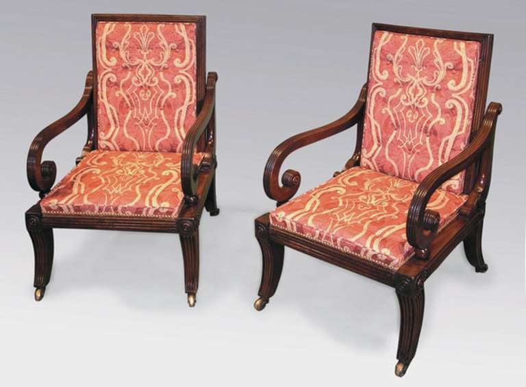 A pair of early 19th century Regency period mahogany library armchairs with unusual sliding action to the seat and back. The chairs having acanthus and roundel carving with reeded scroll arms and frieze supported on saber legs ending on brass