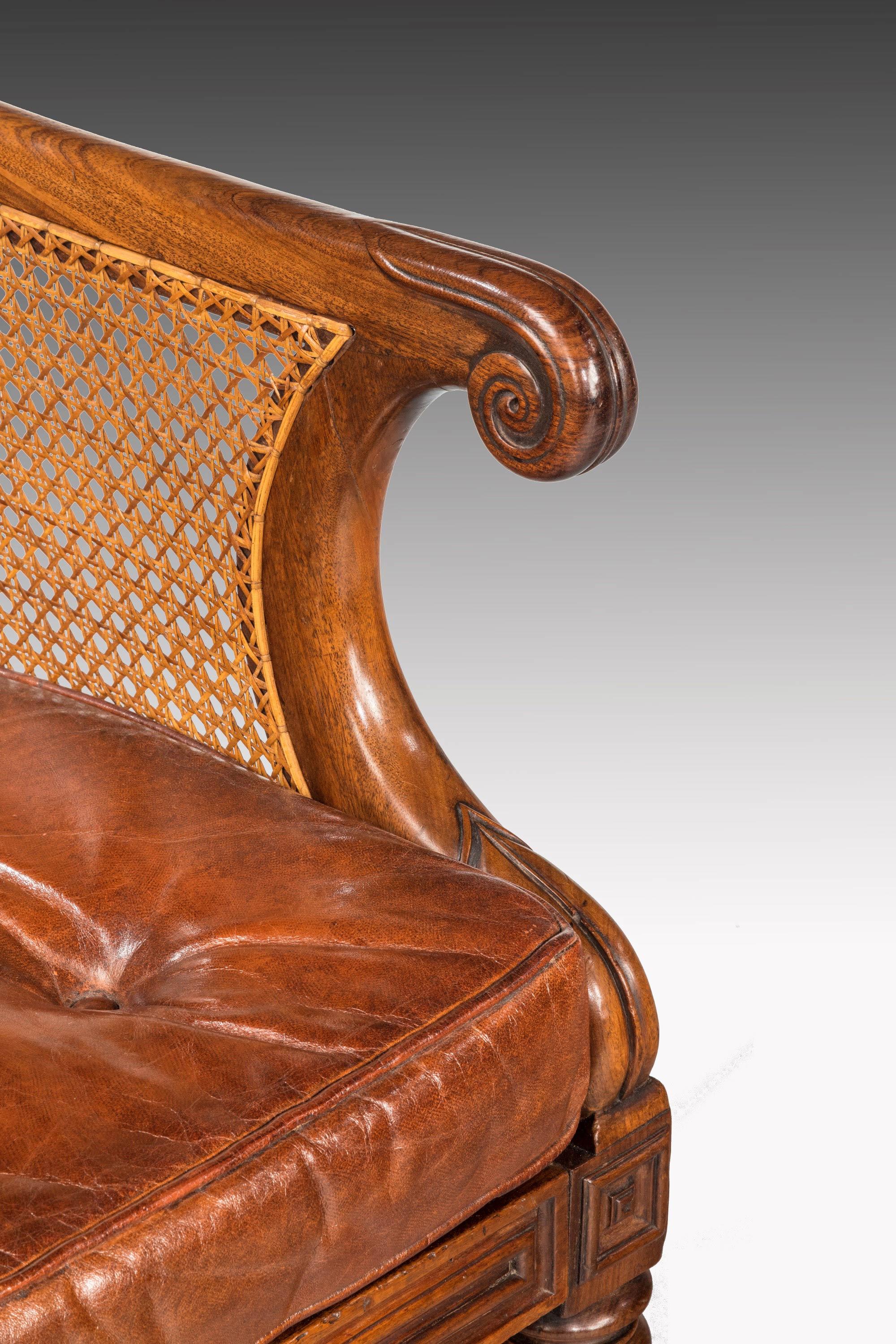 A fine pair of Regency period bergere library chairs. Swept arms over very well carved turned and reeded supports. Original shoes and castors of particularly generous size. Exceptional unrestored condition including the polish.

Measures: Seat