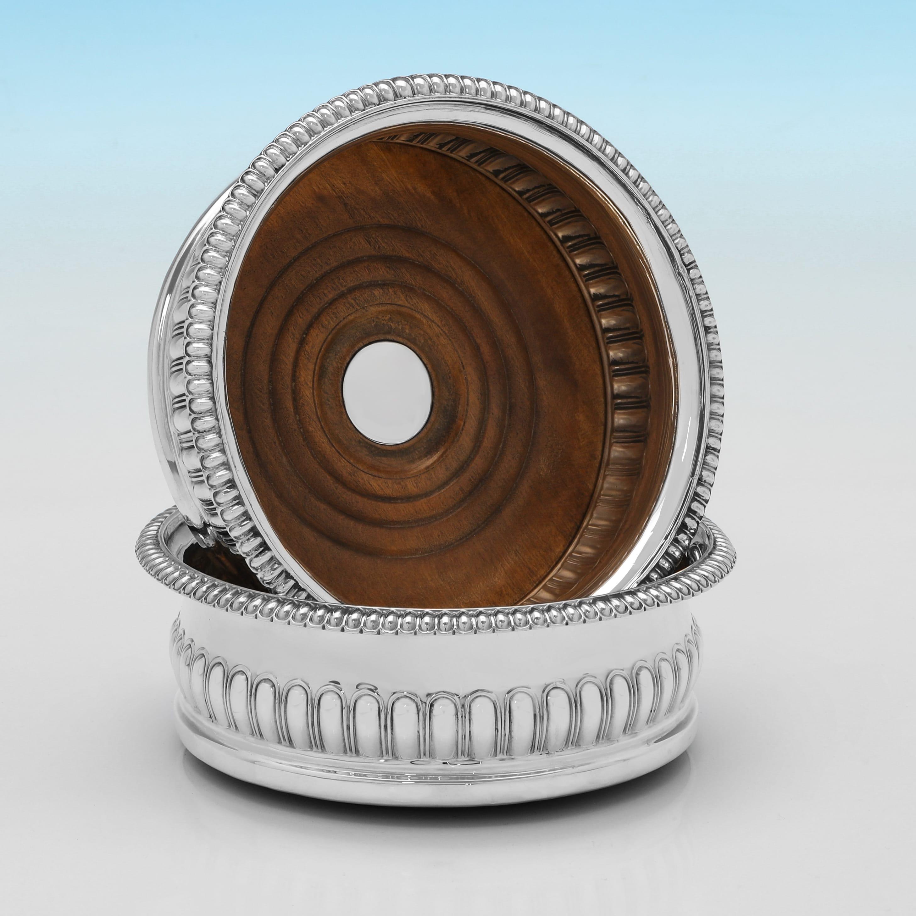 Dieses attraktive Paar antiker Sterlingsilber-Weinuntersetzer aus der Regency-Periode wurde 1818 in Sheffield von John & Thomas Settle gestempelt und zeichnet sich durch eine geriffelte Dekoration, einen Holzsockel mit Silberknöpfen und eine