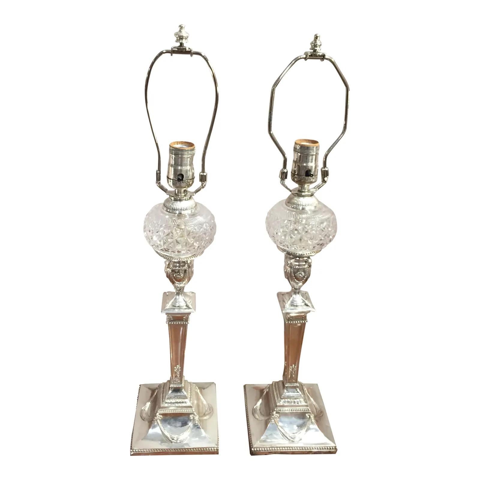 Coppia di antichi candelieri in argento Sheffield trasformati in lampade da tavolo con caratteri in vetro tagliato. La base è decorata con volute e urne. 
L'argento è consumato in alcune zone alte e si nota un po' di rame.
Cablato e in buone