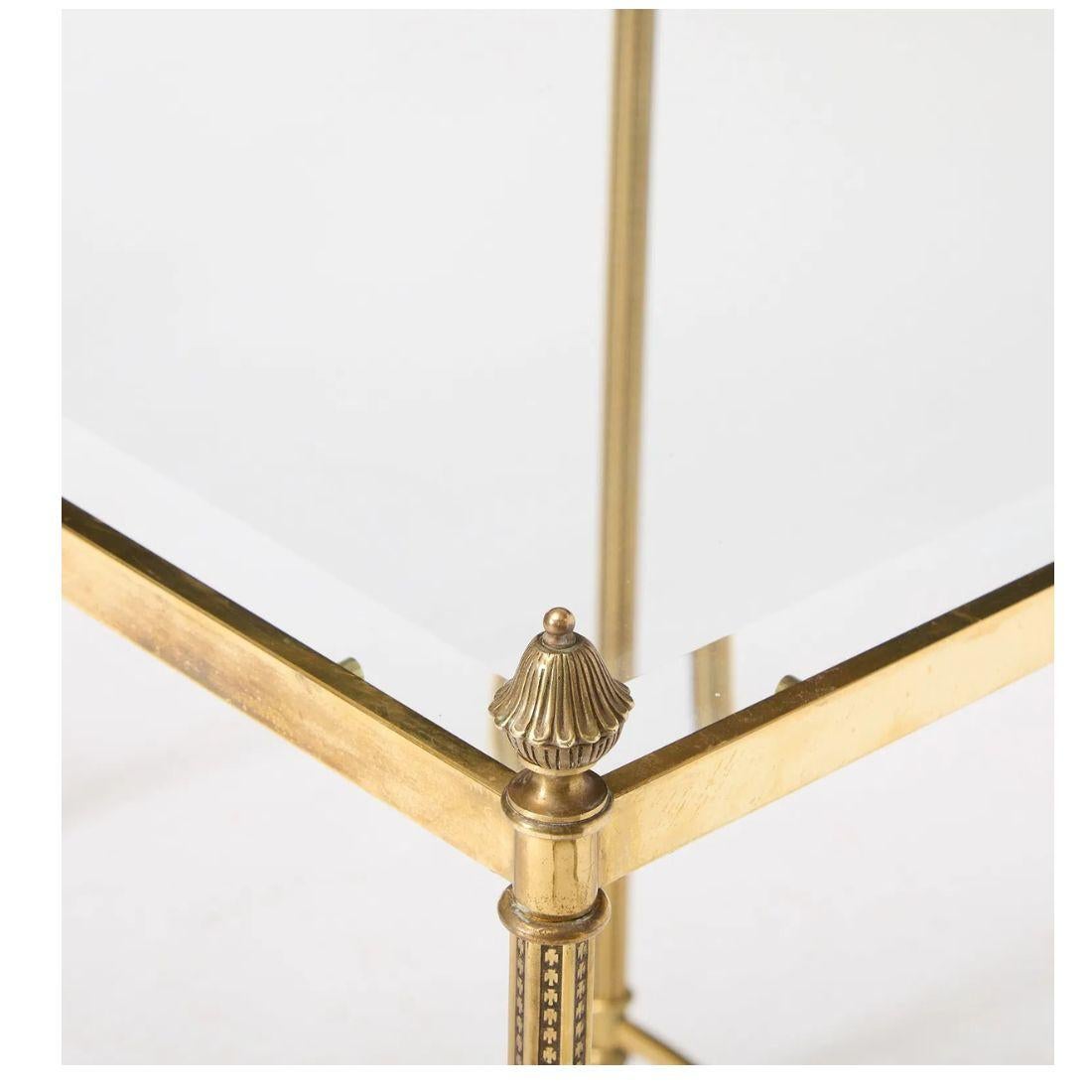 Una raffinata coppia di tavolini in stile Regency unisce l'ispirazione classica a materiali di lusso. Ogni tavolo è caratterizzato da una struttura in ottone scintillante che sostiene un piano in vetro trasparente, offrendo una presenza leggera e