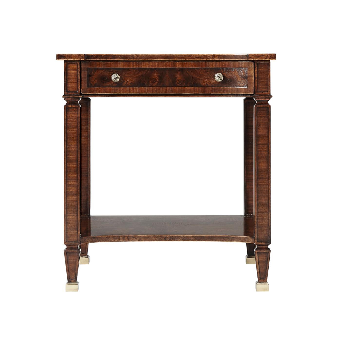 A Regency style mahogany end table with figured elm and rosewood crossbanded, the rectangular top with protruding angular corners and a concave front above a paneled frieze with one drawer, above paneled rosewood legs joined by an under tier, on