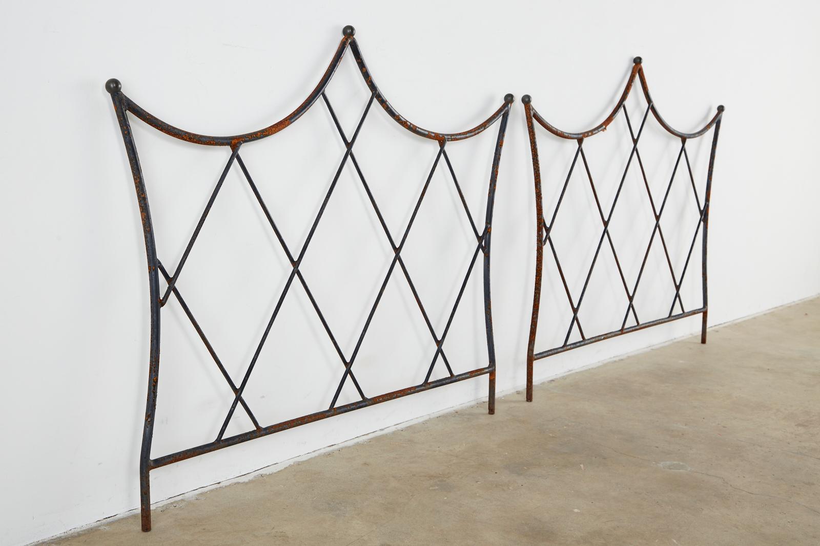 Dramatic mid-century modern pair of twin headboards. Features a handcrafted wrought iron frame with cross hatch pattern design and bronze ball finials on the tops. There is no mounting hardware attached. The iron has a beautifully patinated finish.
