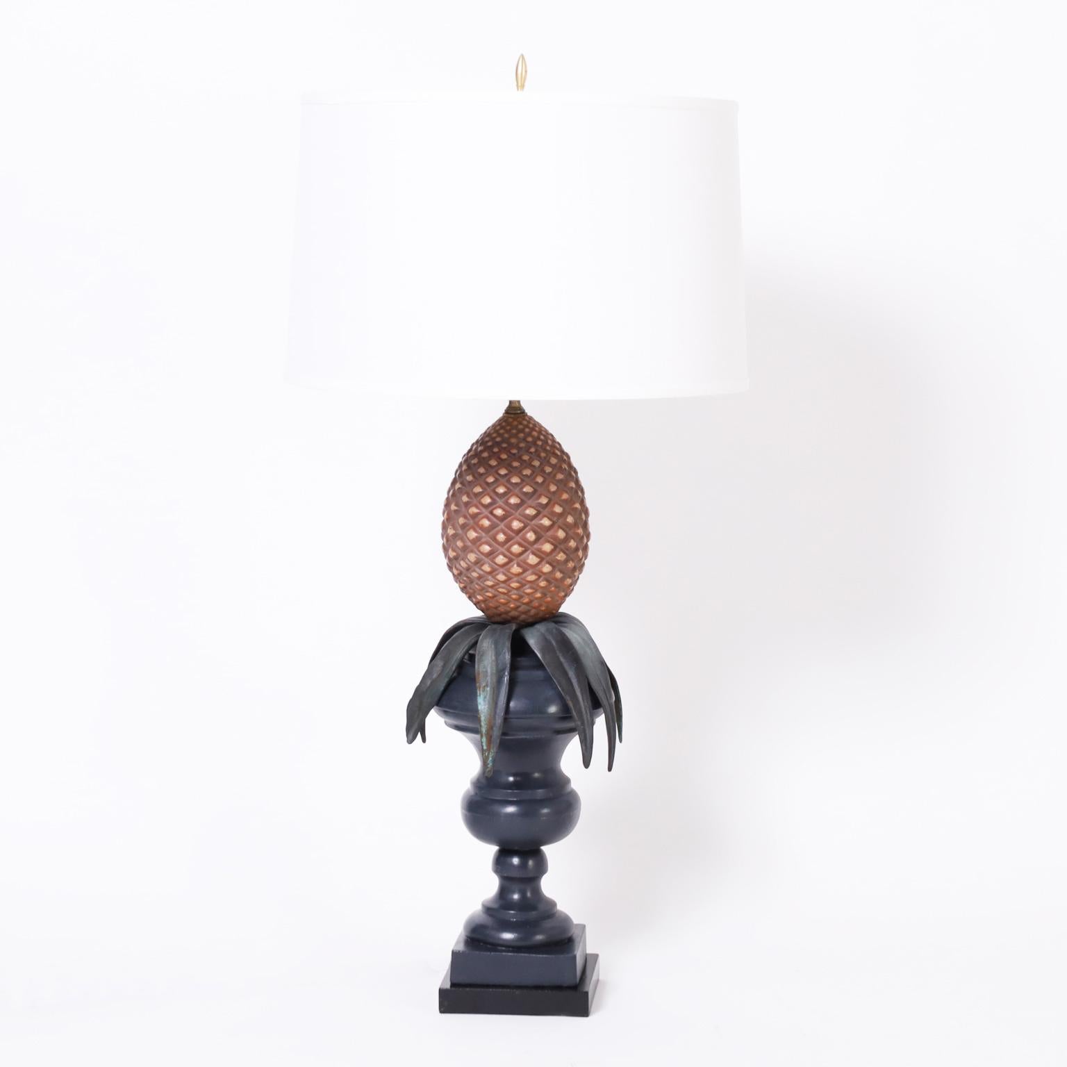 Lofty pair of Italian table lamps having painted metal pineapples highlighted with leather leaves on classic painted metal urns with a double plinth.