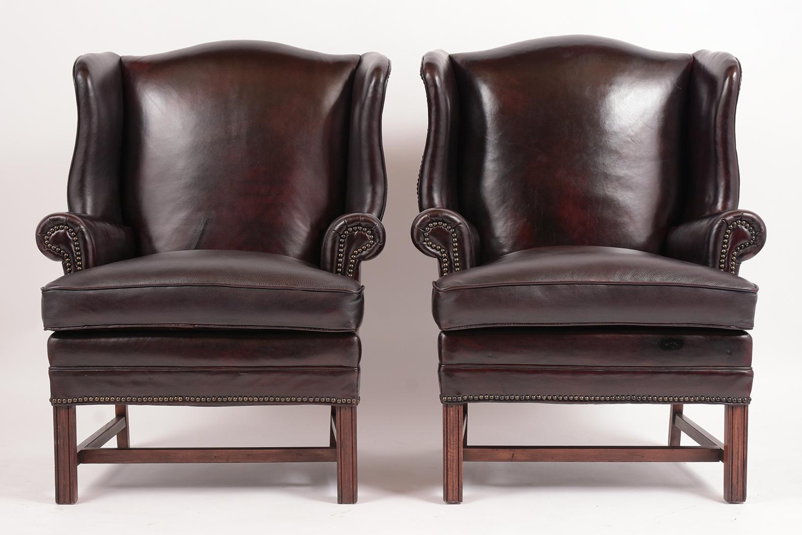 This Circa 1950s Pair of Regency Style Wing Armchair features the original leather upholstery in good condition and has been dyed in a dark Cordova color with a patina finish. This set of Armchairs also features a comfortable single cushion with