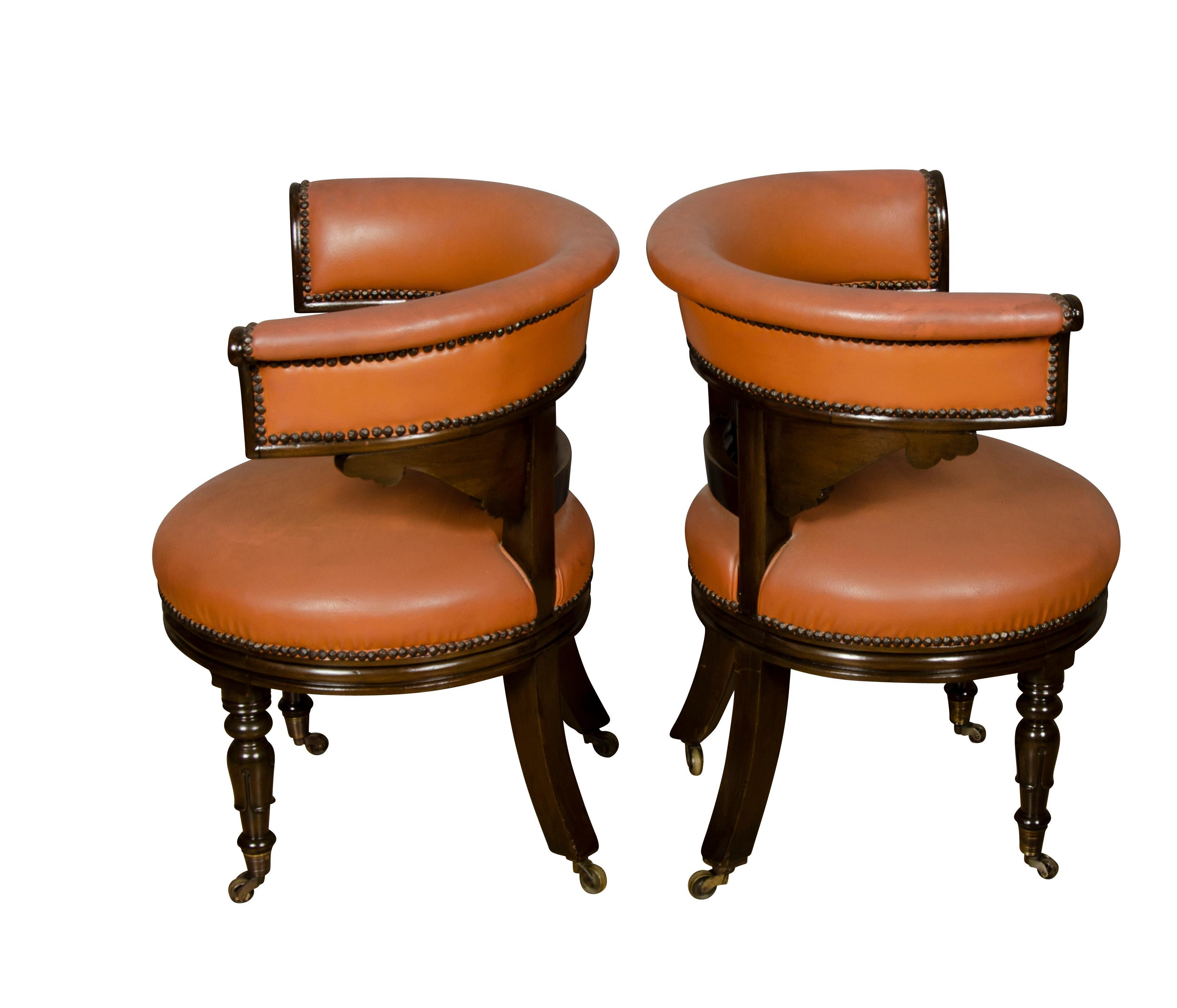 With U shaped backs and circular seats upholstered in brown leather , the backs with carved frames raised on turned legs and casters.