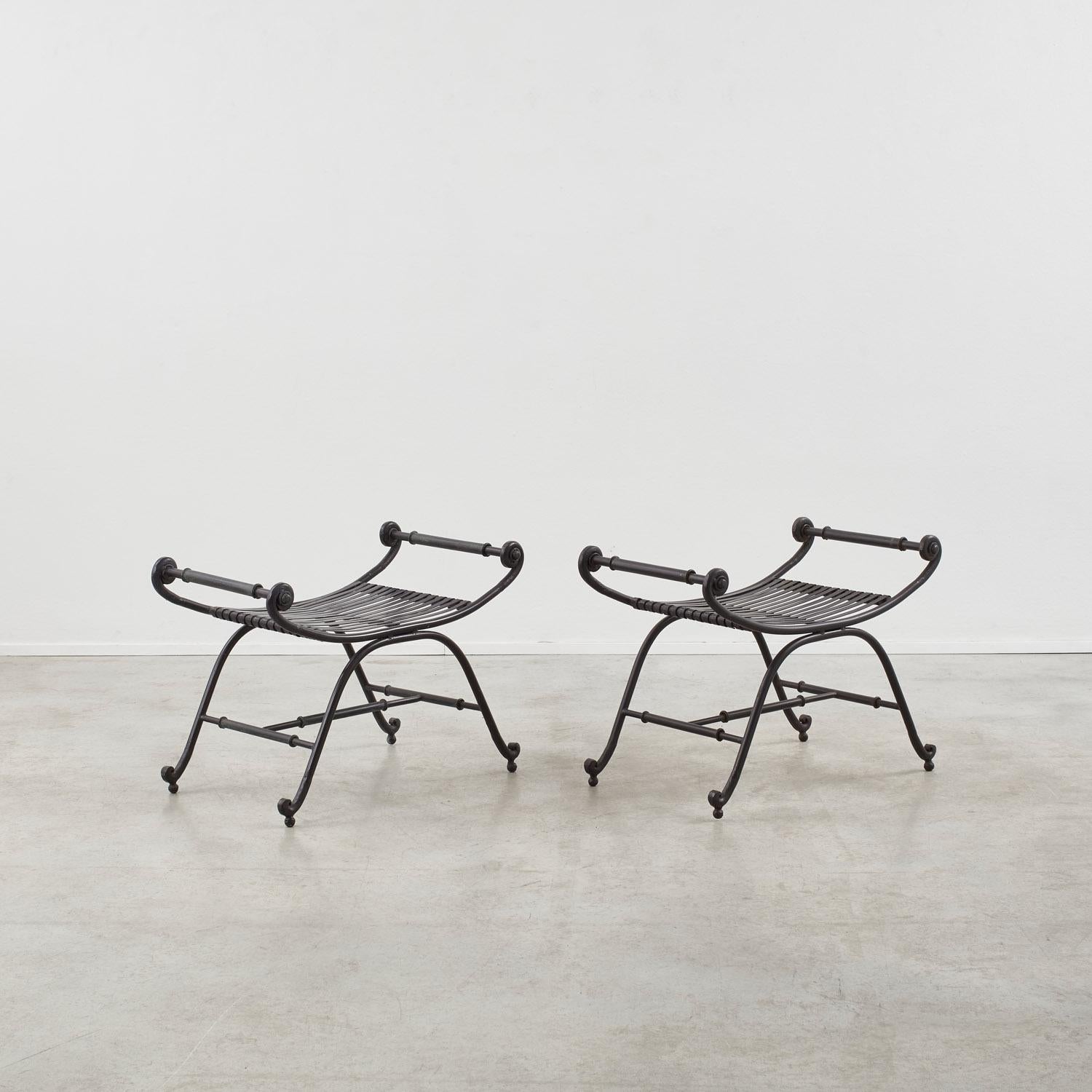 Delicate, graceful, calligraphic in form. This set of metal curule stools is replete with Regency style flourishes – note the spheres on which the scrolling legs rest, as well as line demarcations within the H frame. 

Suited as garden seating, the