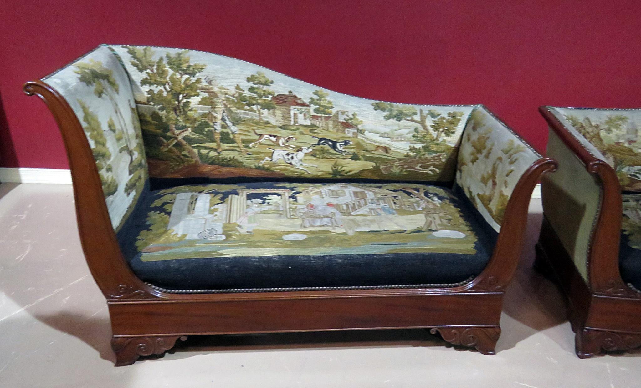 Pair of Regency style recamiers with a sleigh end, dropped shape back, rounded end, nailhead trim, and needlepoint upholstery. The upholstery depicts different scenes of hunting, courtship and even spinning tarn. Beautiful detail and great patina. 