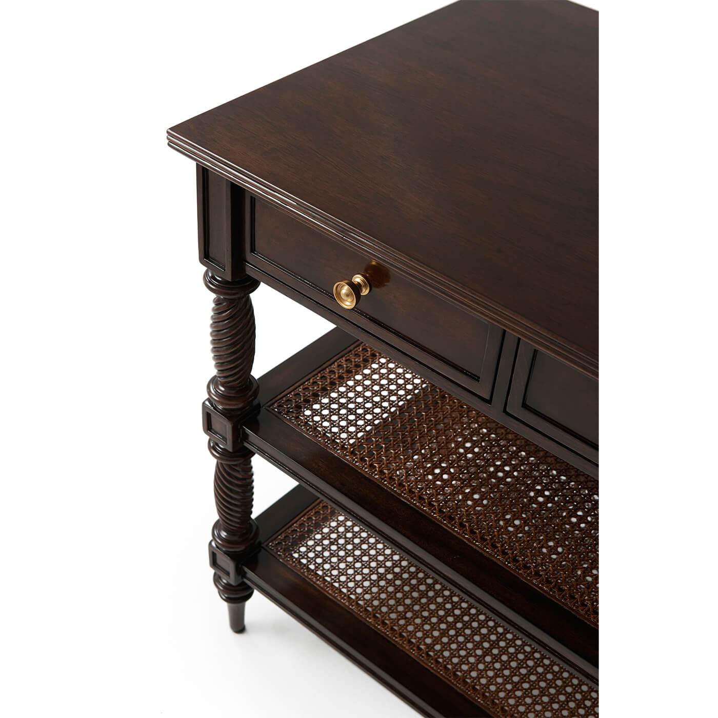 A Regency-style nightstand or side table is a colonial flavored piece with a nod to Anglo-Indian furniture flavors. A framework of spiral turned and tapered legs supports two frieze drawers below a reeded rectangular top. Two caned shelves for