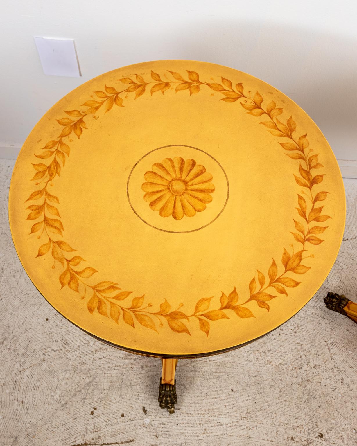 Pair of Regency style painted side tables on a faux bamboo pedestal body, tripod base, and lion's paw feet on castors. The table is further decorated with foliate trim framing a central patera medallion on the tabletop and beaded trim on the table