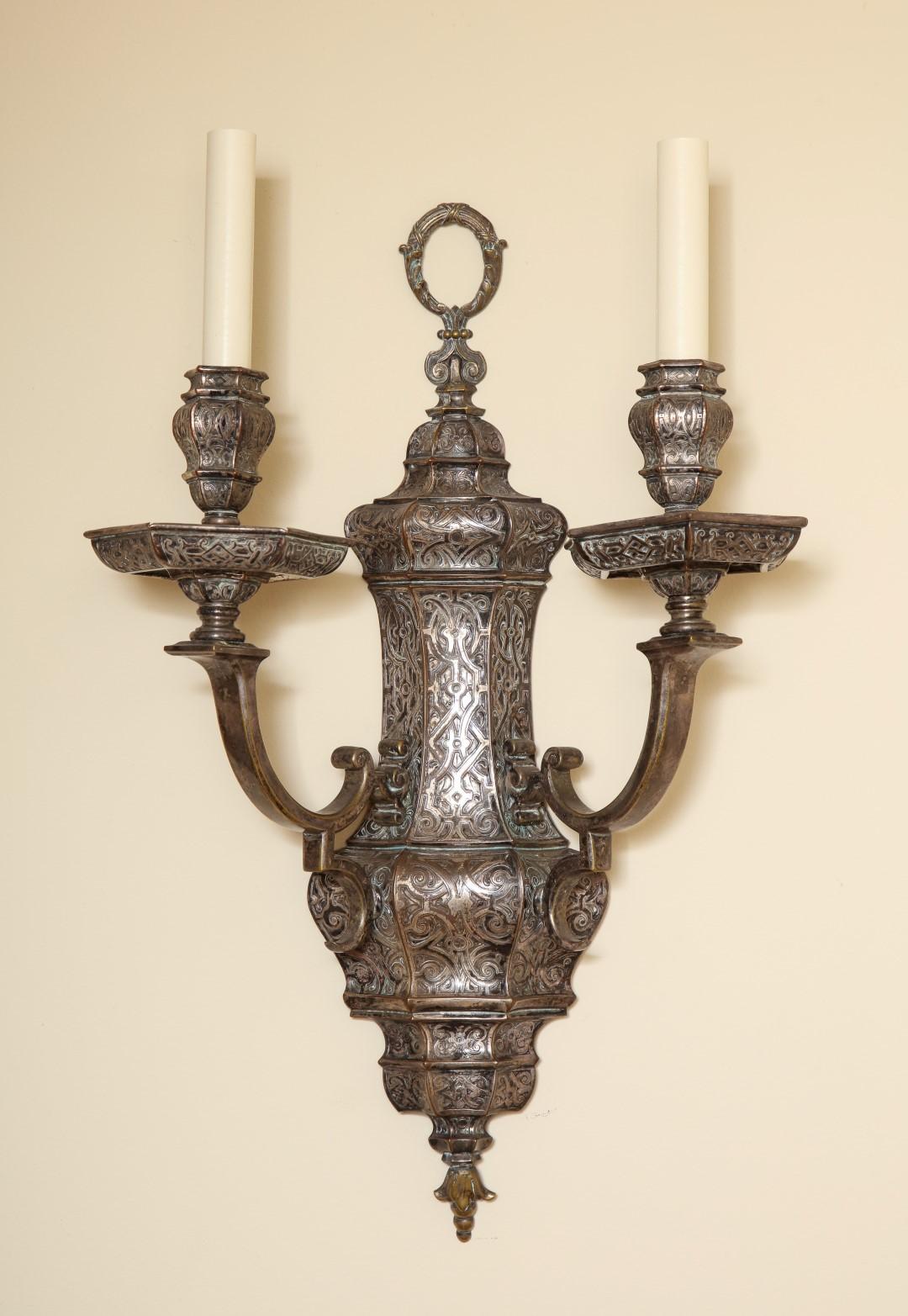 A pair of silvered 2-light wall sconces attributed to E. F. Caldwell. Each sconce has two arms, and is silver-plated with an engraved design. Each is signed with 