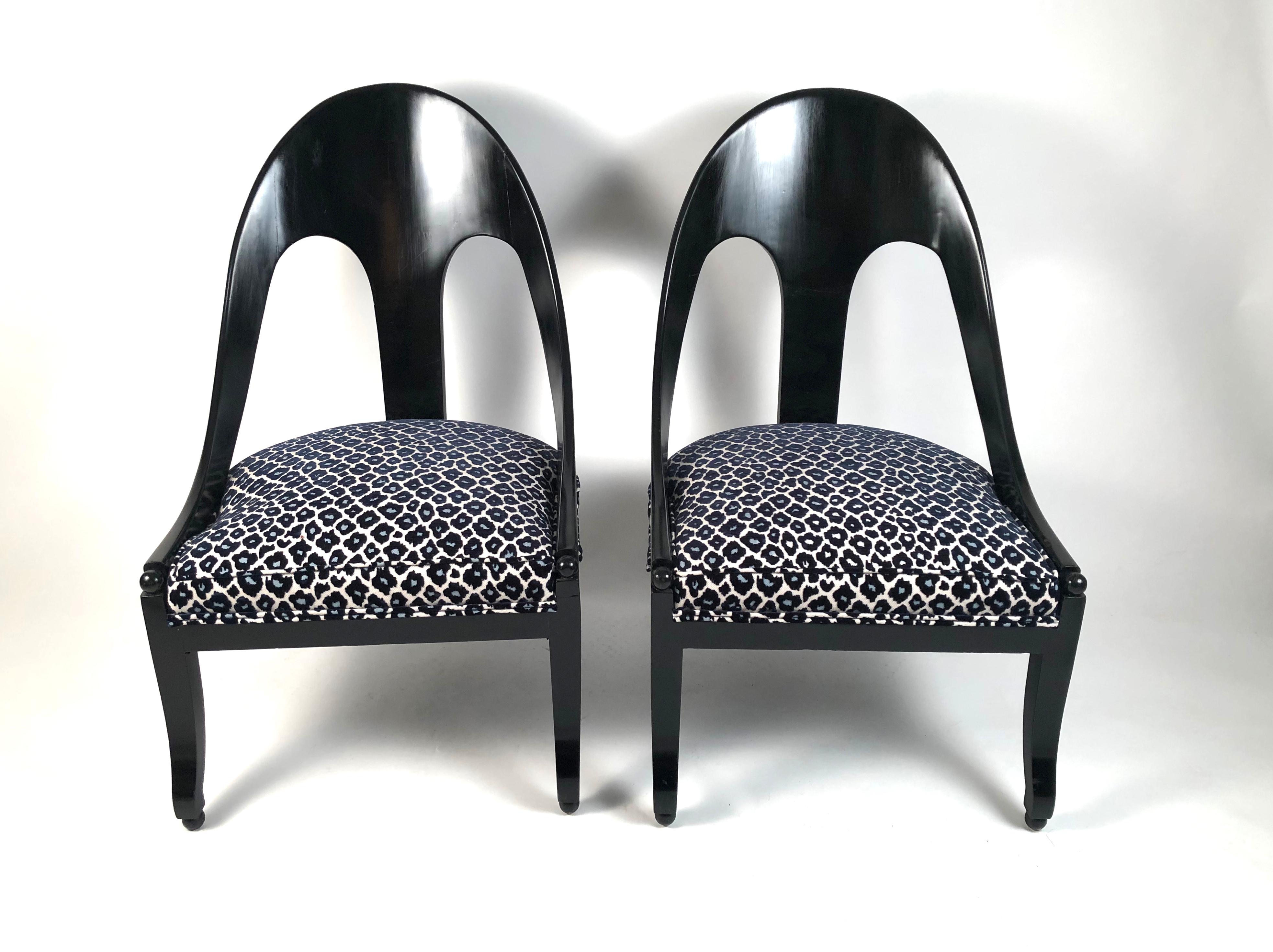 A pair of stylish and comfortable Regency style ebonized black wood spoon back chairs with newly upholstered seats in a high quality cut velvet blue and black leopard print. The sculptural curved back with central back splat is over a generously