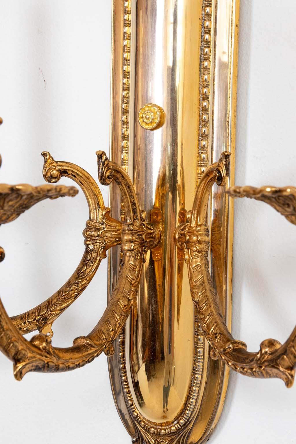 Pair of large scale Regency Style three arm brass Sconces. Wired and ready to use. New cream colored candle covers. Good overall condition. includes mounting hardware.