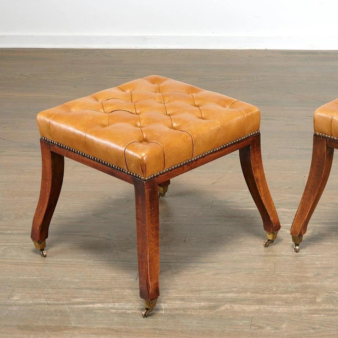 Good pair of Regency style Tobacco saddle leather button tufted stools on splayed mahogany legs ending in brass cups and casters.