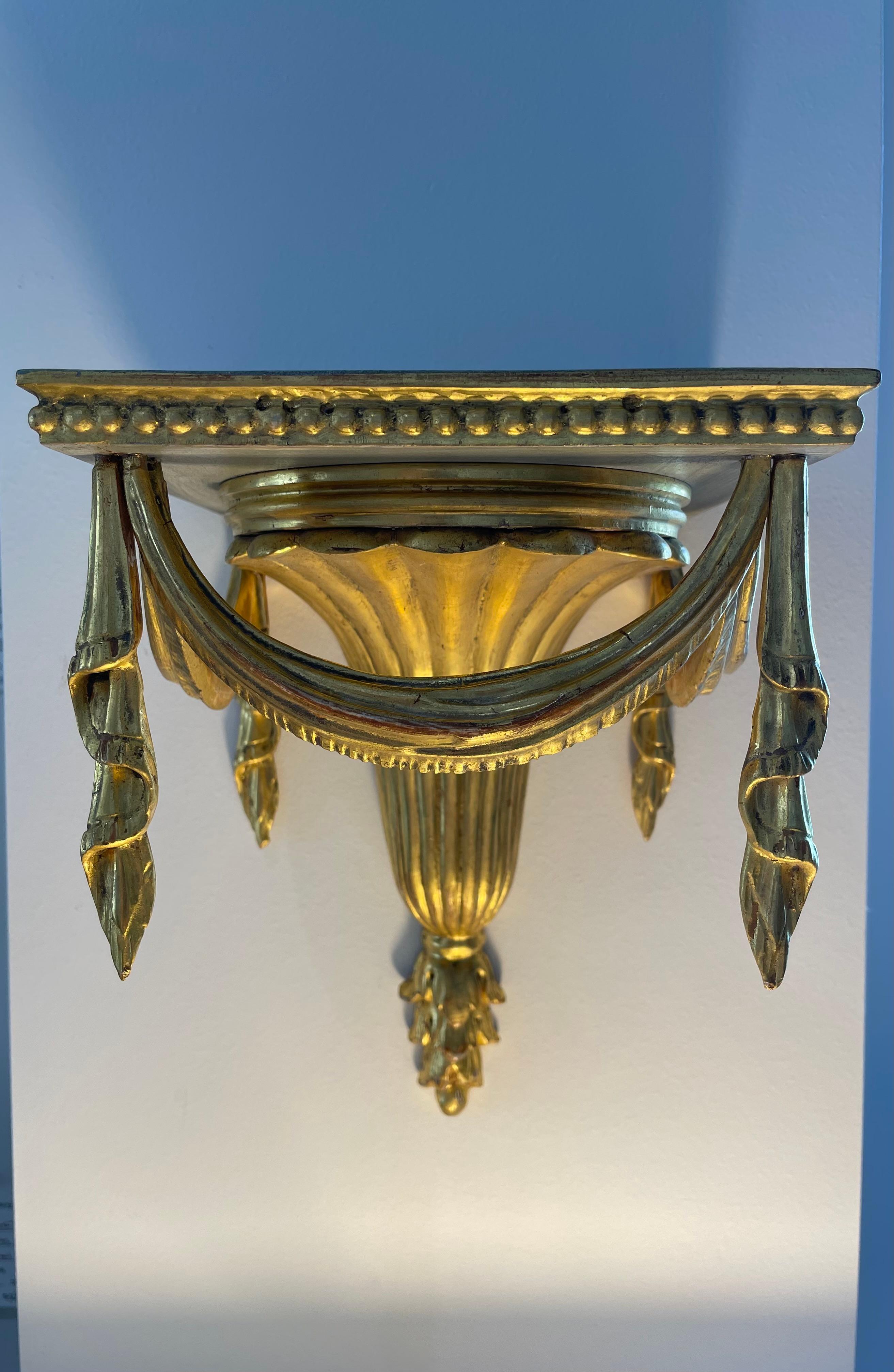 Cet ensemble élégant et chic de consoles murales italiennes de style Regency, sculptées à la main, date des années 1920-1930.  Les pièces  sont dorés, et le dessus et le dessous des supports sont peints en gris tourterelle foncé.  

