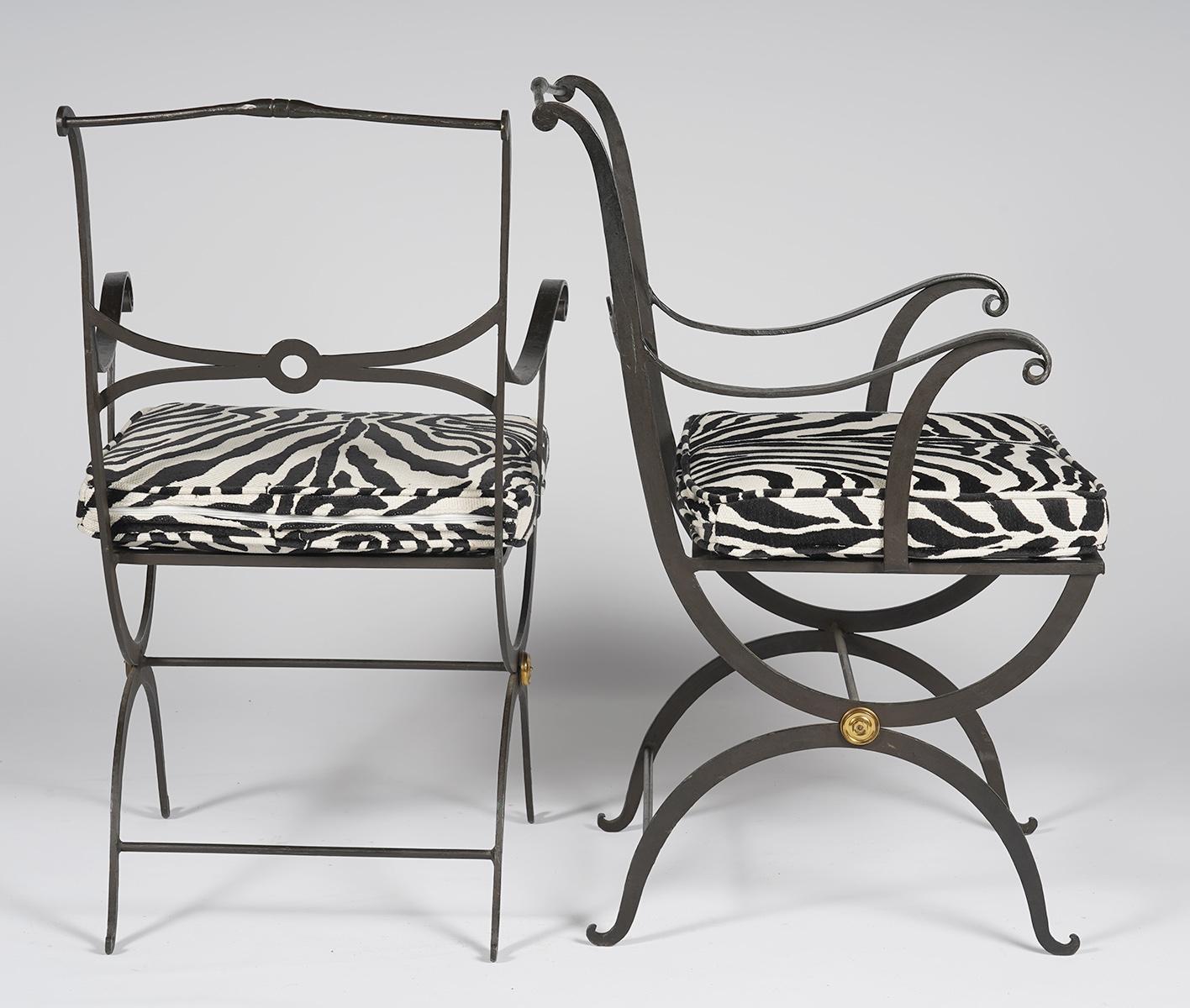 This pair of painted wrought iron stylized Regency armchairs feature Curule style legs centering brass rosettes and elegantly designed backrests. The recent custom made zebra pattern cushions make the combination 'tres chic'. The chairs date to the