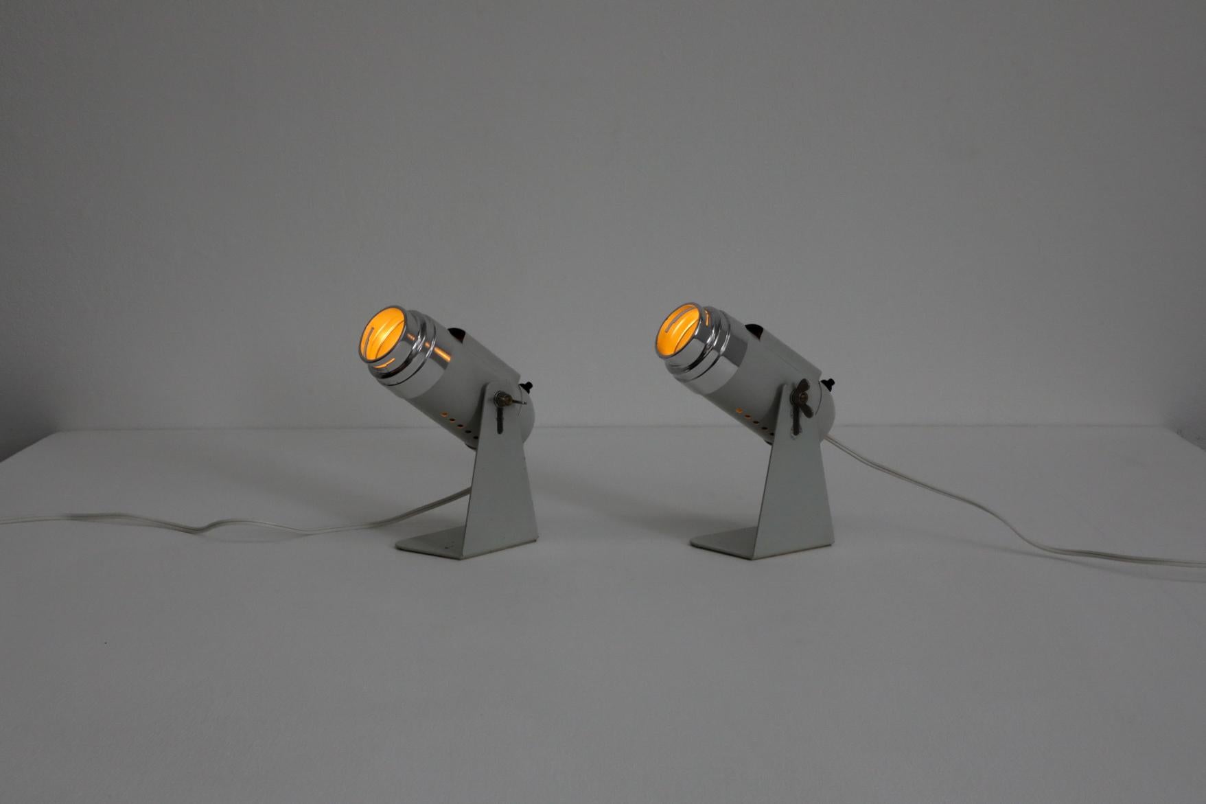 Coppia di applique da tavolo o da parete in metallo grigio chiaro in stile industriale Reggiani con anelli cromati. Fessura nella parte superiore del faro e nell'anello cromato per gel o gobo (non inclusi). Le luci ruotano e si stringono con un dado