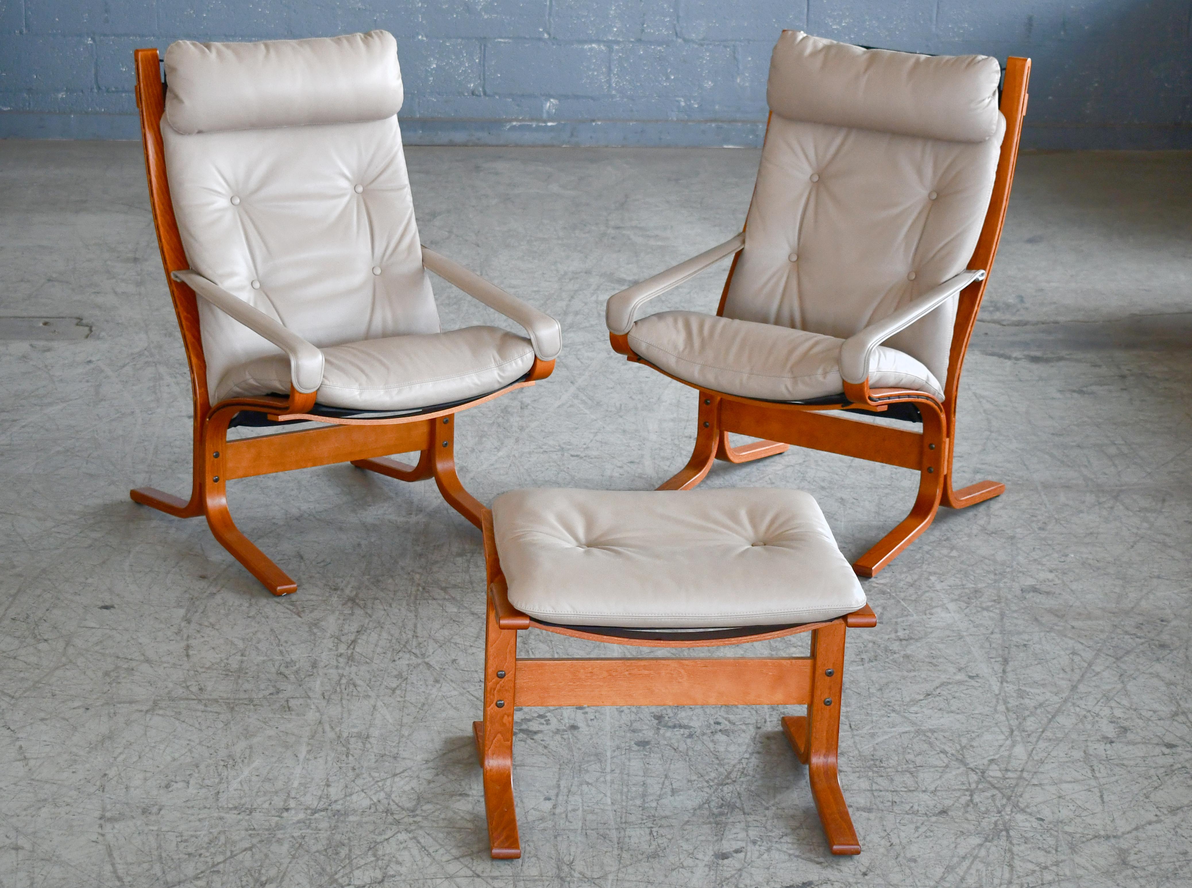 Great pair of highback Siesta chairs in light grey leather with one matching ottoman and light brown stained bentwood beech frame. Designed by Norwegian design icon, Ingmar Relling in the late 1960s and manufactured by Westnofa of Norway. We are not