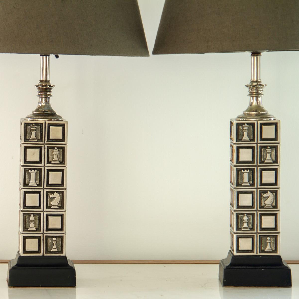 A pair of chess board designed lamps with hammered and brushed metalwork depicting the checkerboard and playing pieces, set on wooden ebonised stepped base

These lamps were designed by The Rembrandt Light Company who started operations in