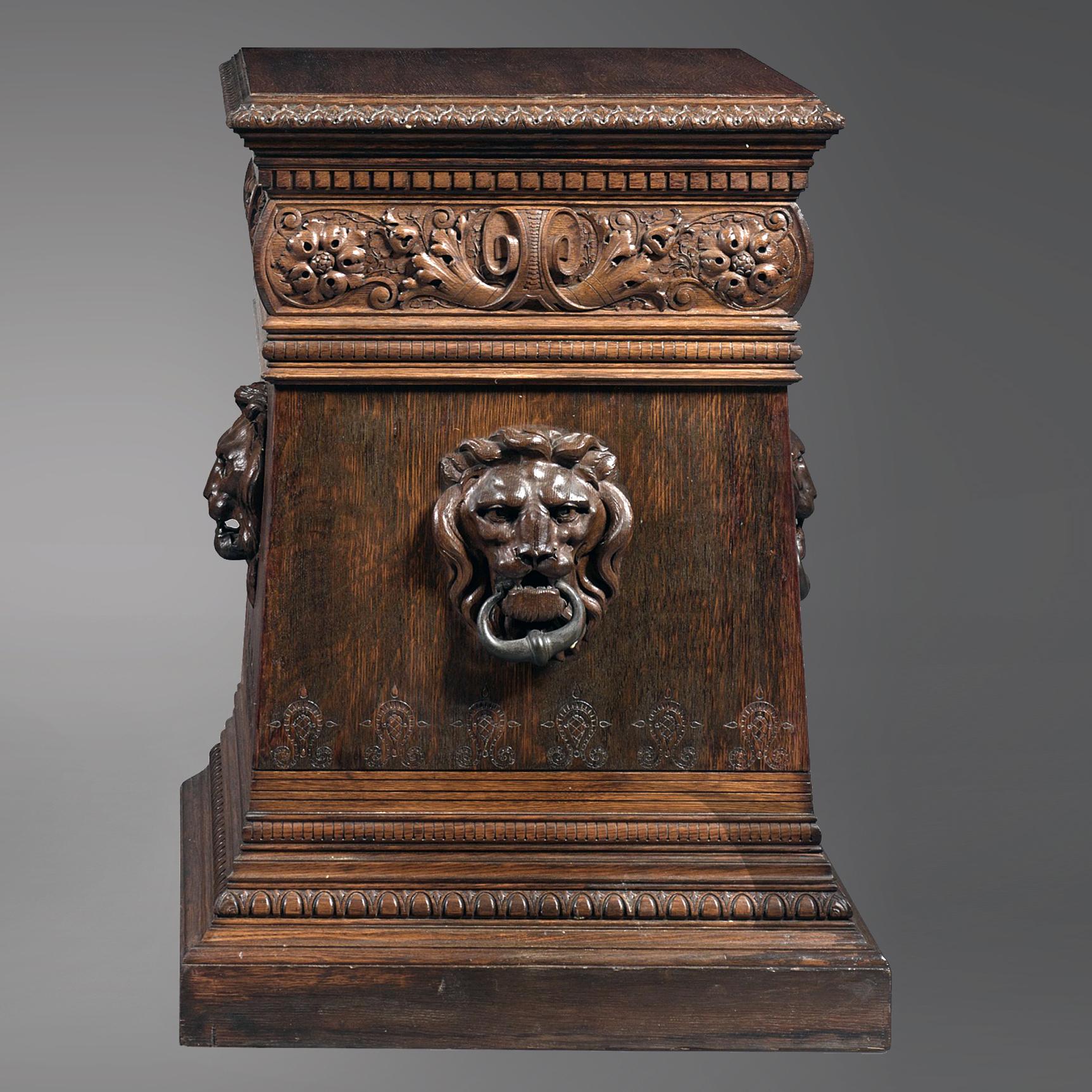 A finely carved pair of Renaissance Revival oak pedestals. 

Each pedestal features a finely carved lions mask to each side supporting wrought iron ring handles. 

Possibly American, Circa 1880. 

Dimensions of tops:
Width 66.5cm /