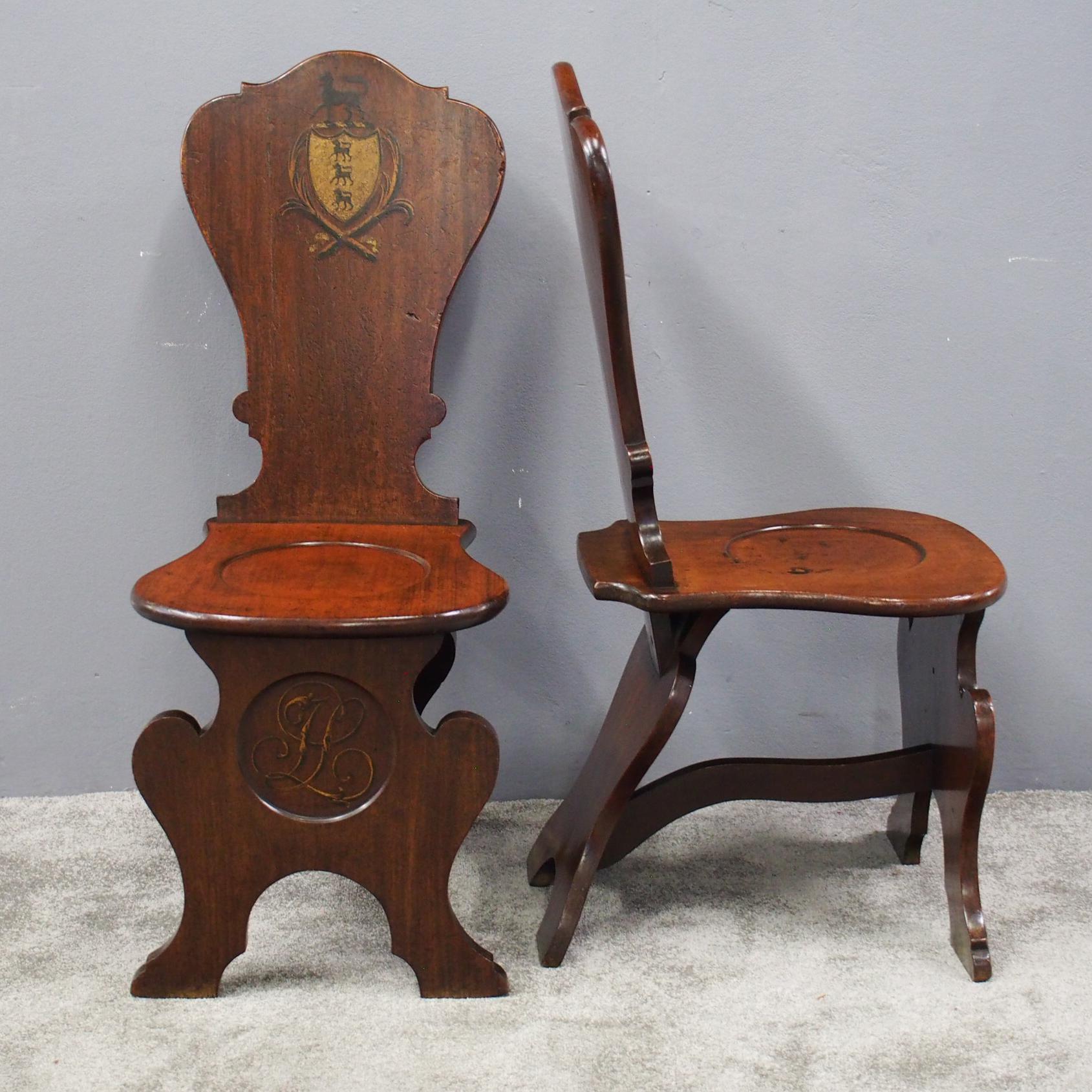 Rare pair of early George III mahogany hall chairs in the Renaissance Sgabello style, circa 1790. The tall cartouche shaped backs with hand-painted coat of arms over a solid, shaped seat with solid shaped support to the front containing a roundel