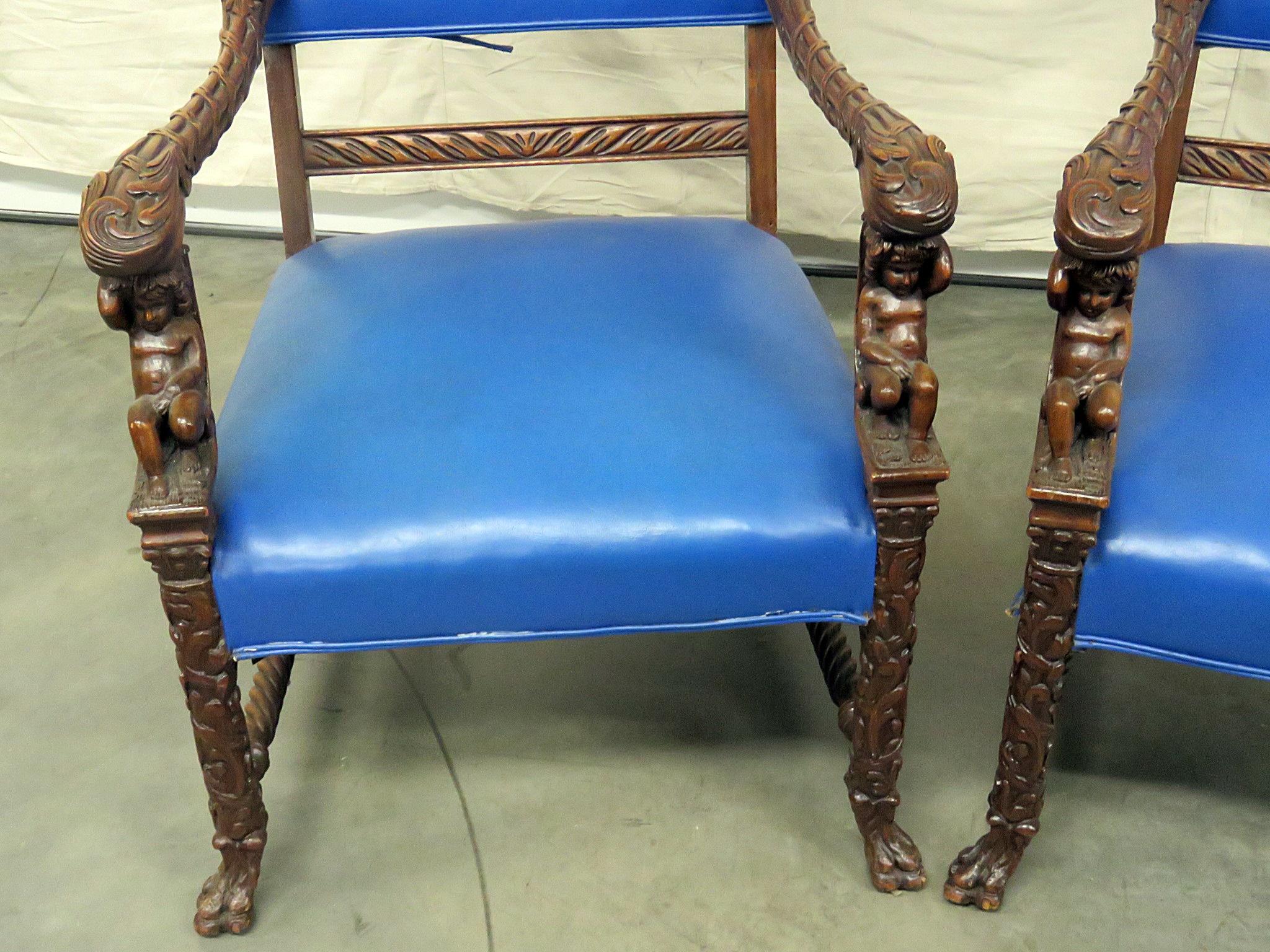 Pair of Renaissance style carved throne chairs, attributed to Horner, with cherubs, paw feet and leather upholstery.