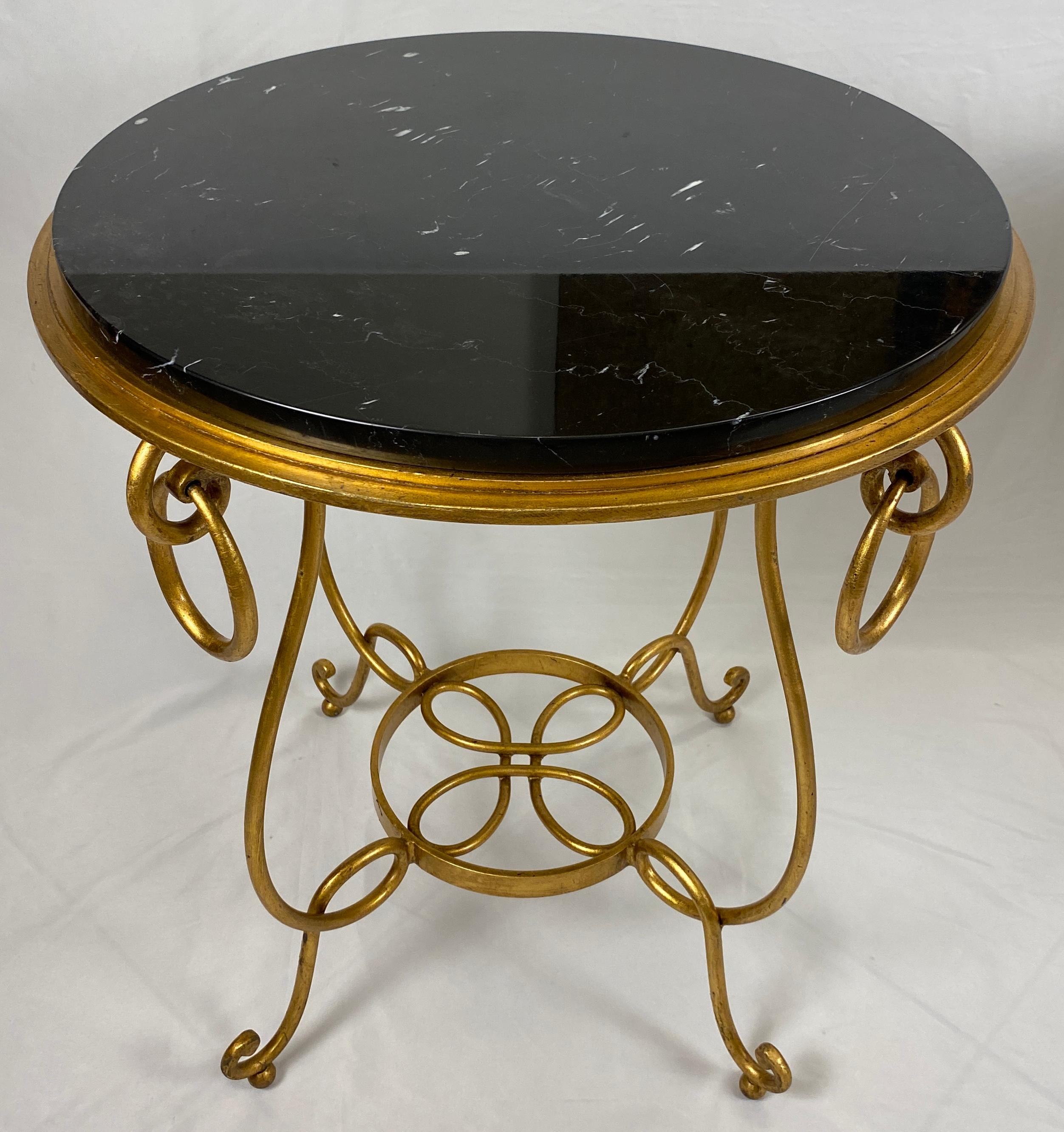 Exquise paire de tables d'appoint en fer et marbre noir, réalisées dans le style et à la manière du designer français René Drouet. Le fer artisanal a une finition dorée et est décoré d'accoudoirs et de pieds à volutes. Les pieds sont reliés à un