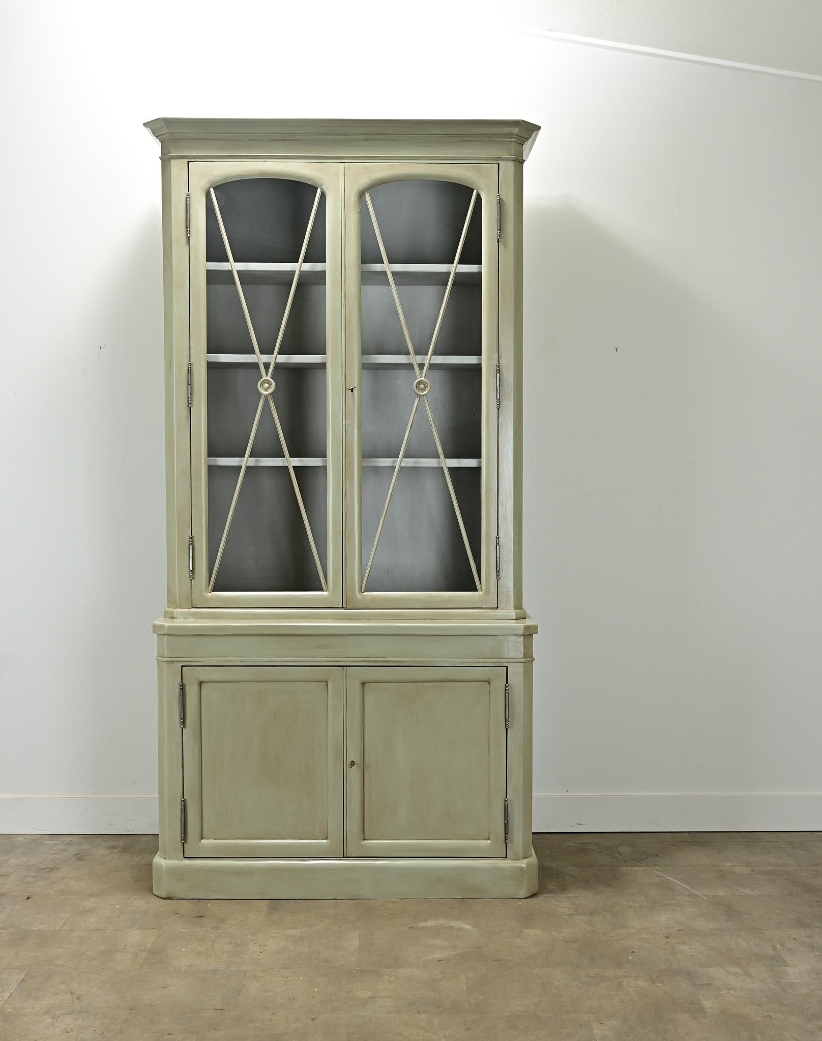 A custom pair of bibliotheques made in the French Louis Philippe style. Each bibliotheque is made of solid poplar with a layered custom paint finish. The top of the cabinets have a pair of arch top glass doors that open with a new lock and key to an