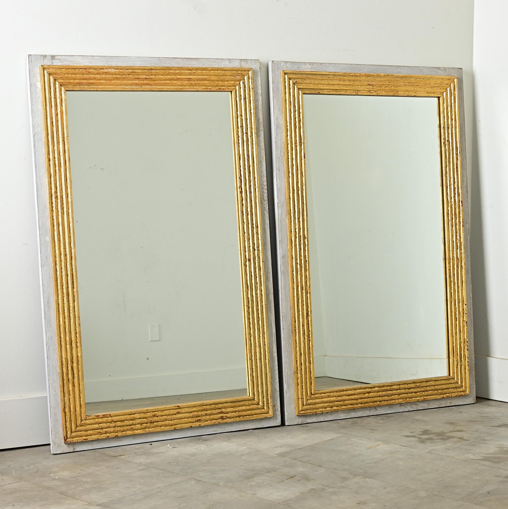 A timeless pair of mirrors, 20th century reproductions that channel the orderly sophistication of 19th century French originals. Entirely hand-crafted, the back panels of each mirror are painted a nuanced “French Gray” that is lightly patinated.
