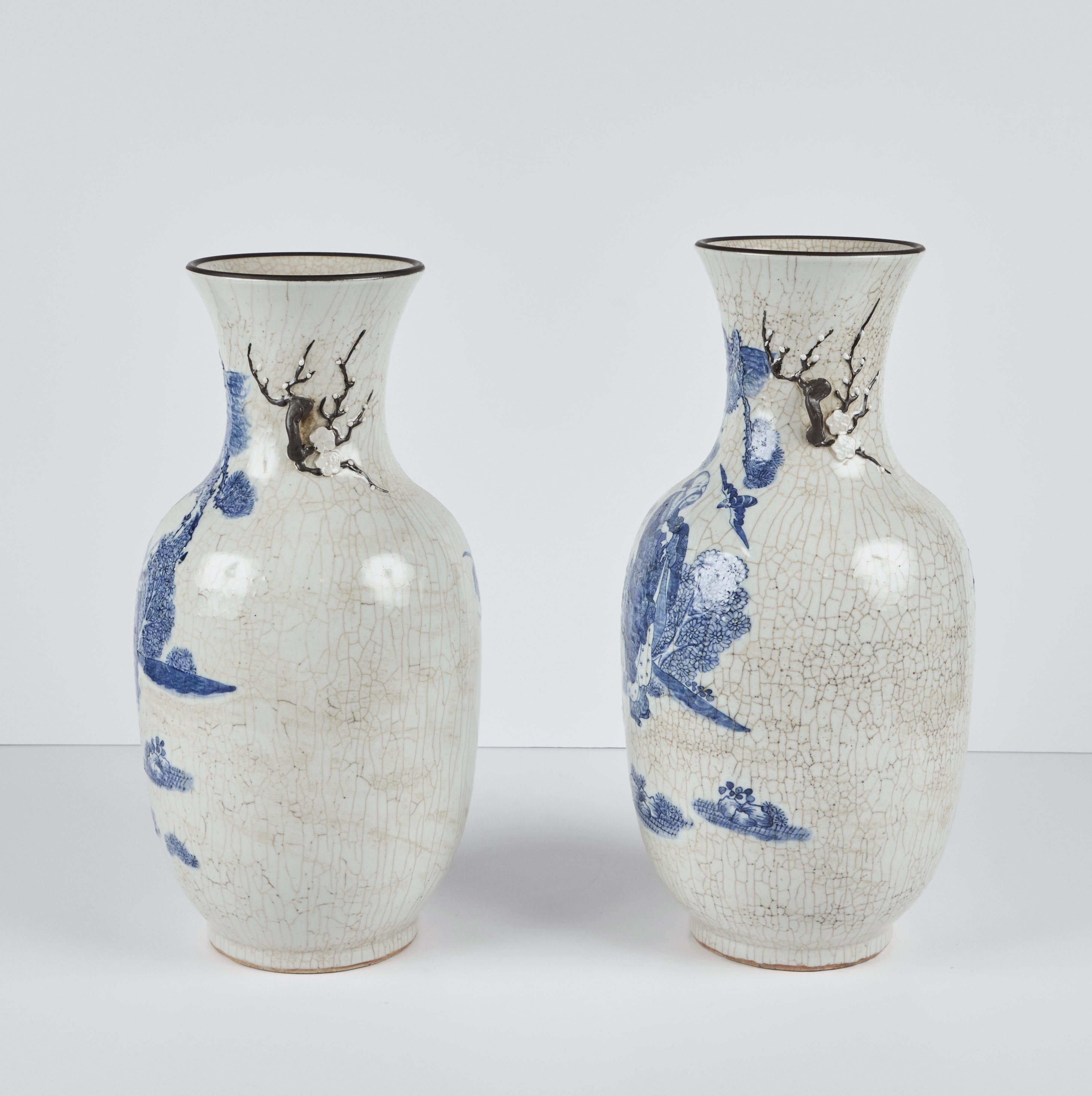 Pair of Chinese, hand-painted porcelain vases featuring figures in nature, with a crackle glaze and branch formed handles with raised flowers