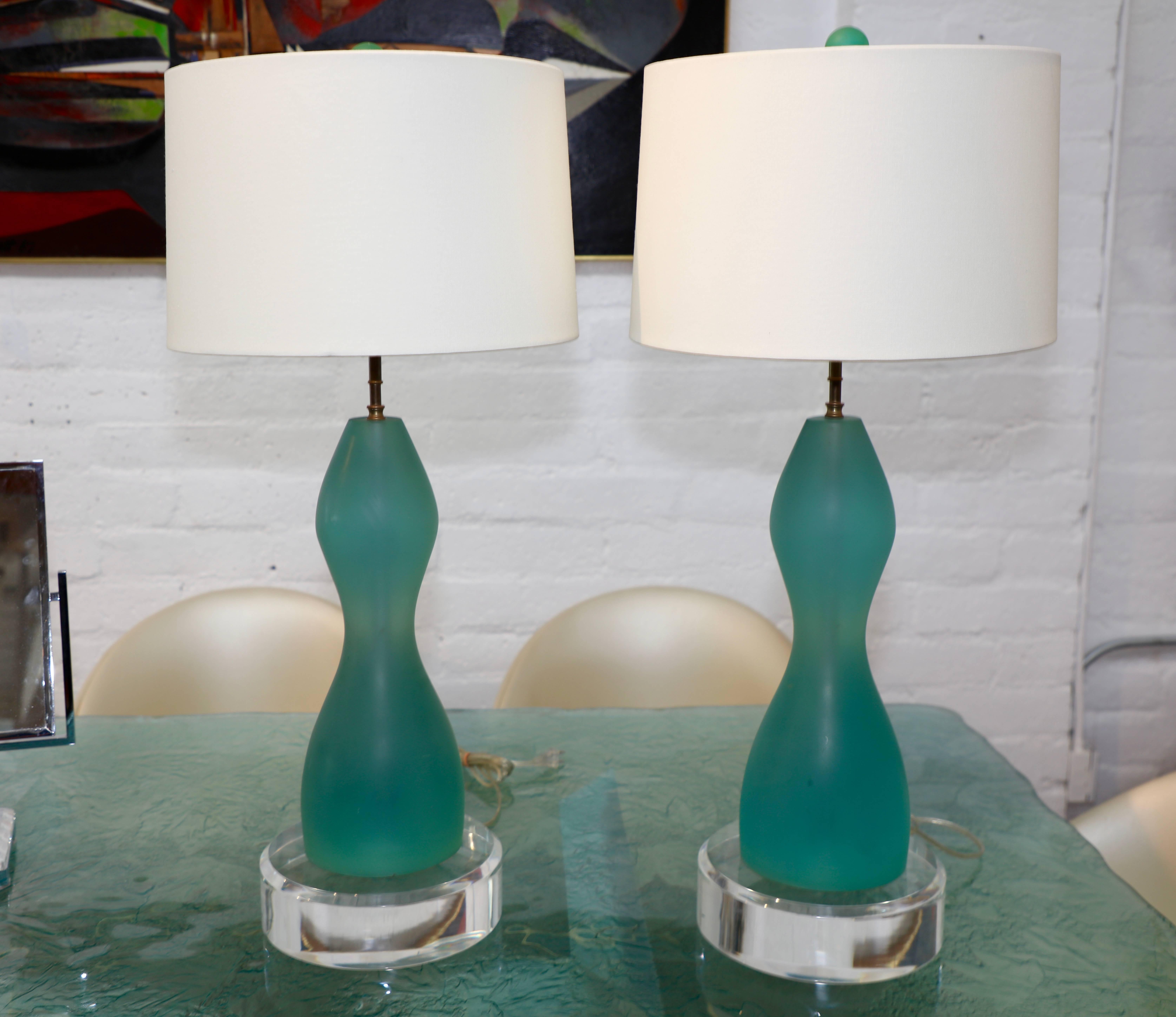 A nice pair of resin lamps in a aqua color. They feature Lucite disc bases that are 3 inches thick. These disks are not attached the lamps just sit atop them and are likely later additions. New shades. A nice pair of lamps. Some slight marks and to