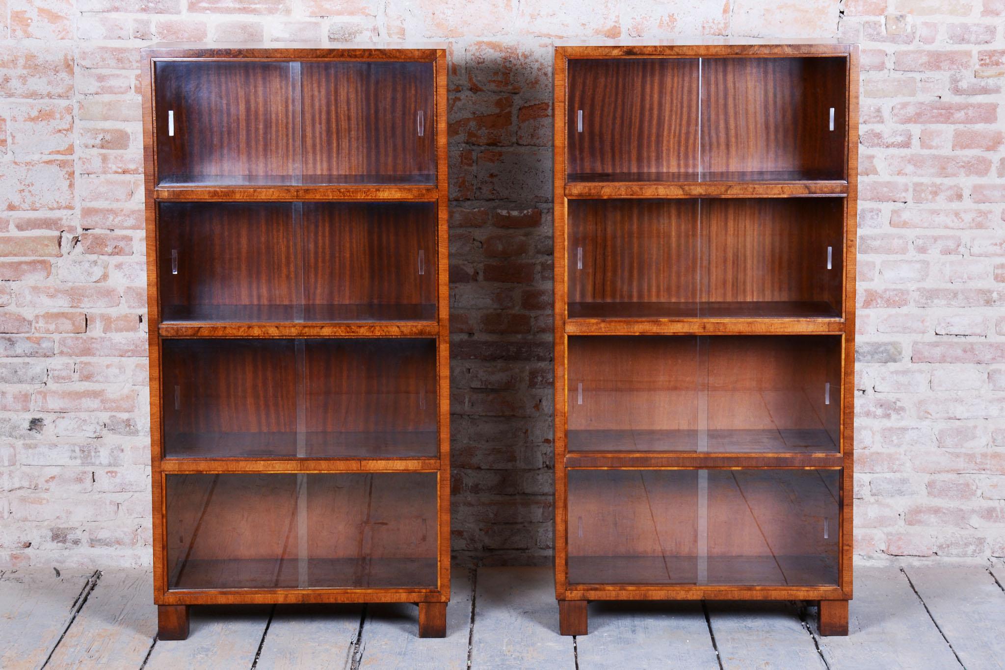 Dieses elegante Paar Art-Déco-Bücherregale stammt aus dem frühen 20. Jahrhundert. Sie sind aus Walnussholz gefertigt und haben Schiebetüren aus Klarglas. Die Bücherregale wurden von dem Architekten Oldřich Liška entworfen.

Die Bücherregale wurden