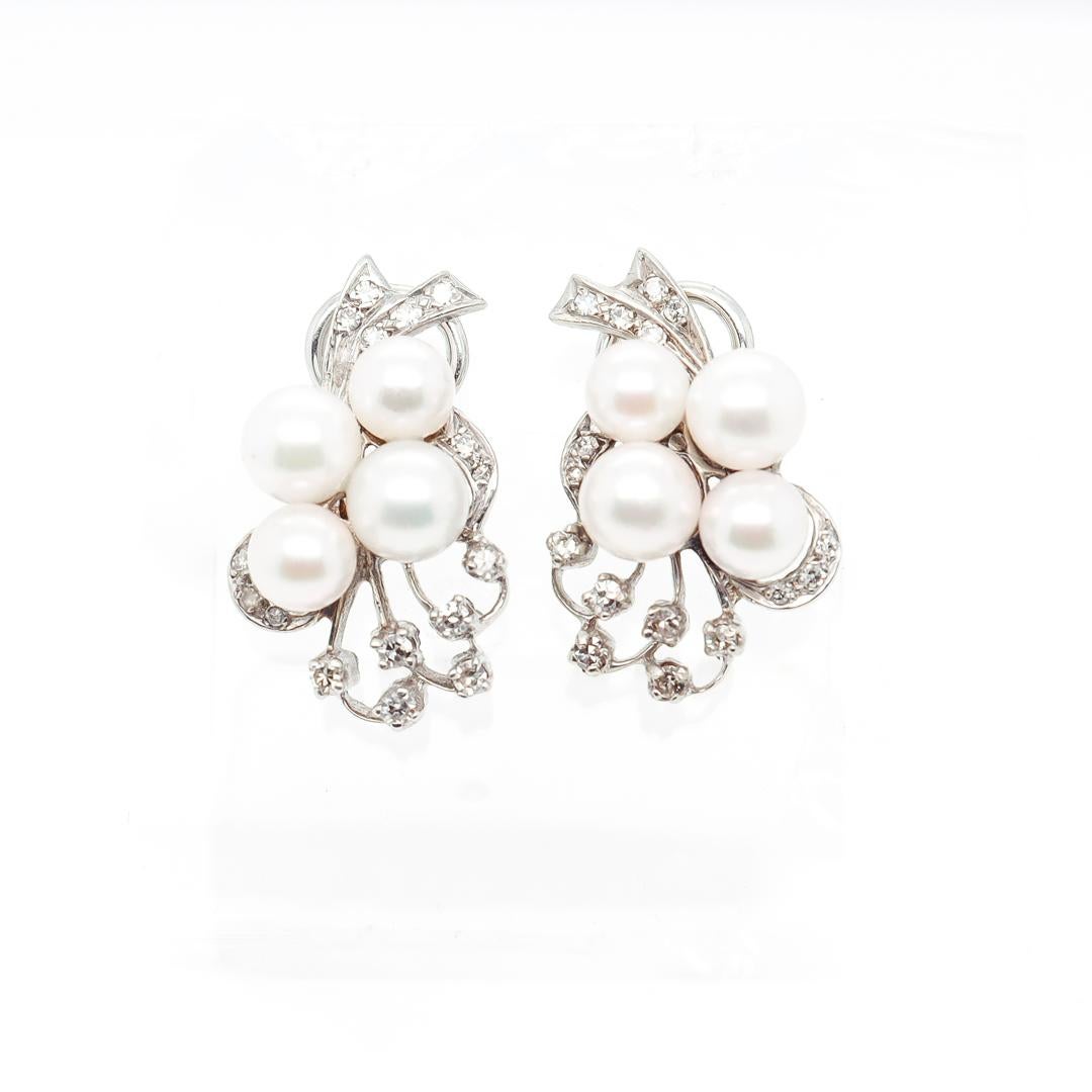 A fine pair of Mid-Century earrings.

In 14 karat white gold.

Each set with 4 pearls to its center and throughout with white single-cut diamonds.

With a circa 1970's conversion to omega clip backs (perfectly functional but not the prettiest