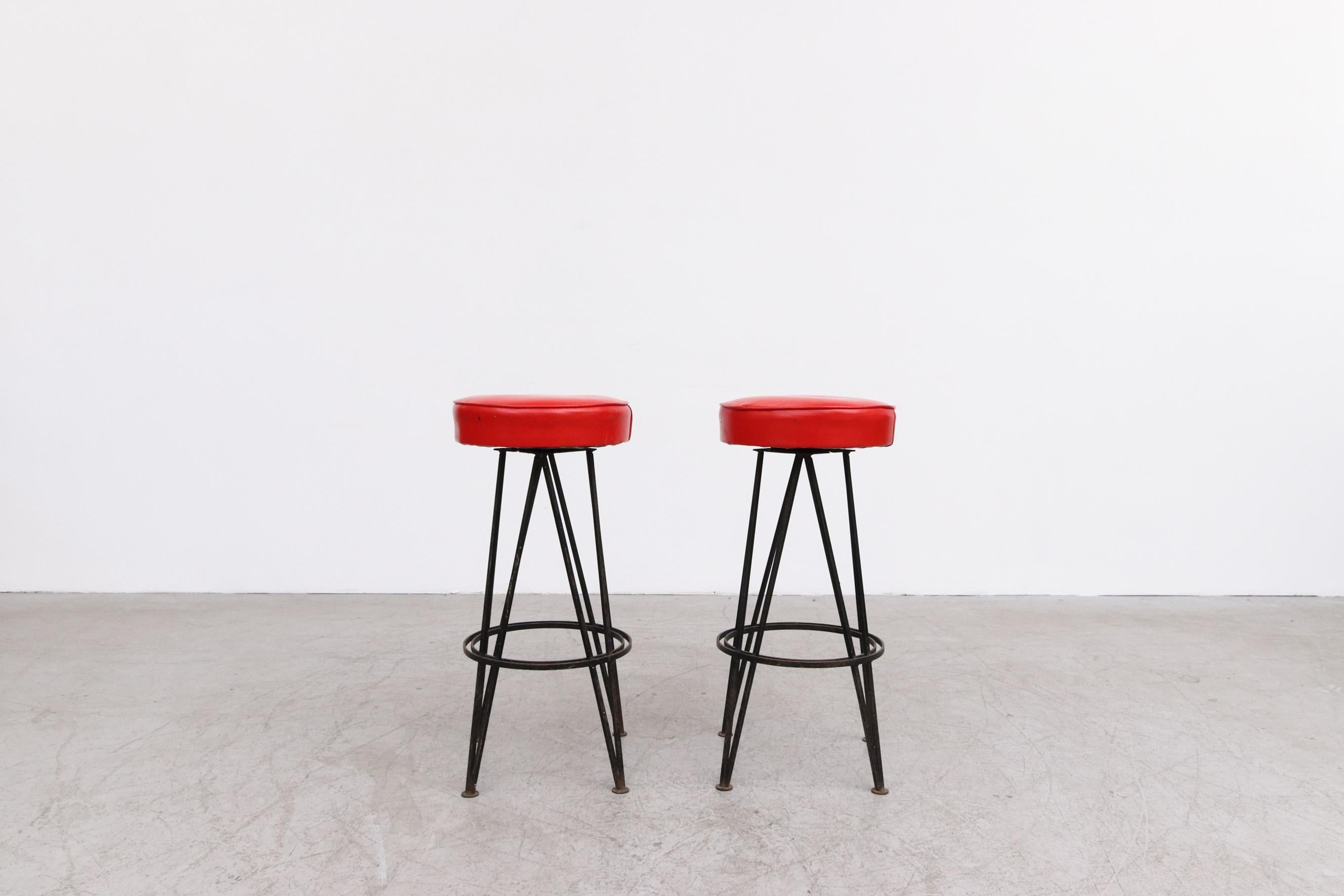 Pair of Retro 50's Bar Stools with Rotating Red Skai Seats and Black Enameled Legs. In original condition with visible wear to seats and frame. Wear is consistent with their age and use. Set Price.
