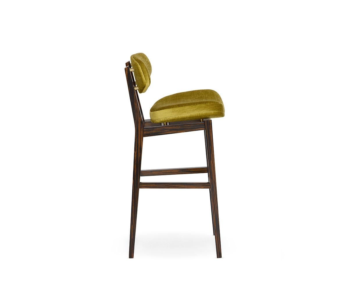 This piece seamlessly combines a retro vibe with contemporary lines, offering both functionality and style. The design features exposed legs that support a wing-shaped padded backrest, providing excellent support and comfort. The platformed seat,