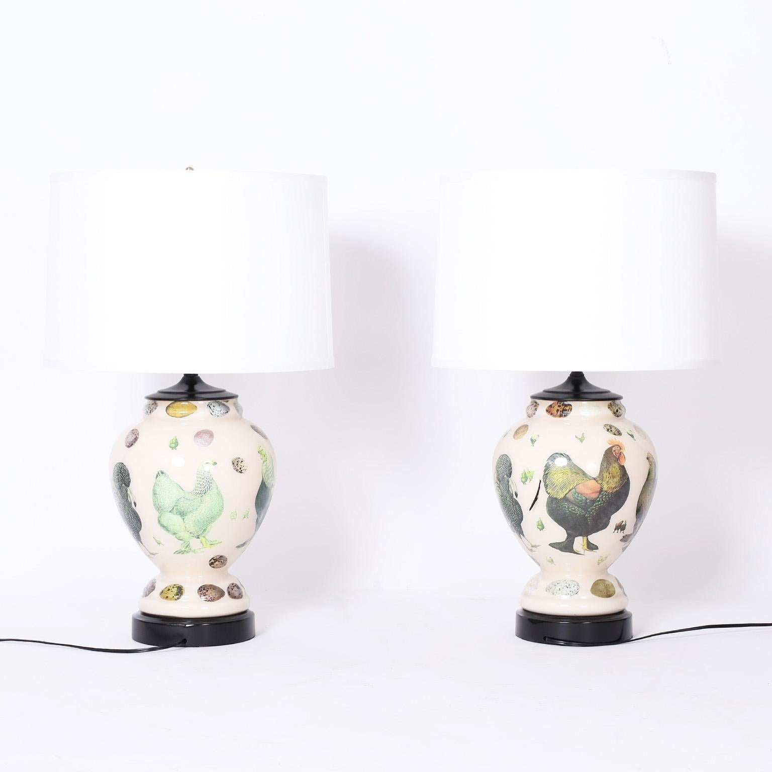 Charming pair of table lamps with classic form decorated with a reverse decoupage technique under glass of roosters and eggs on an off white background.