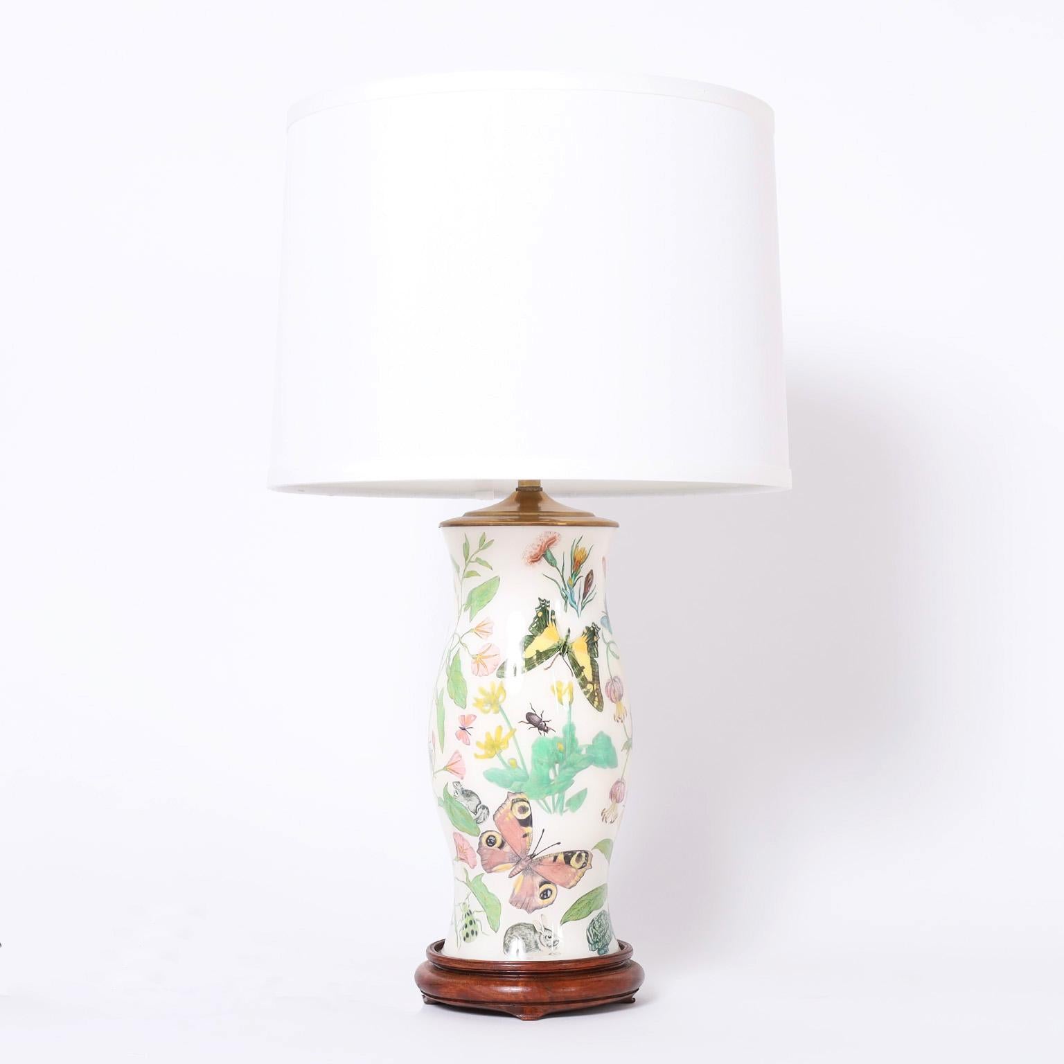 Delightful pair of table lamps with reverse decoupage flowers, butterflies, and bugs on a white background with classic form on wood bases.
