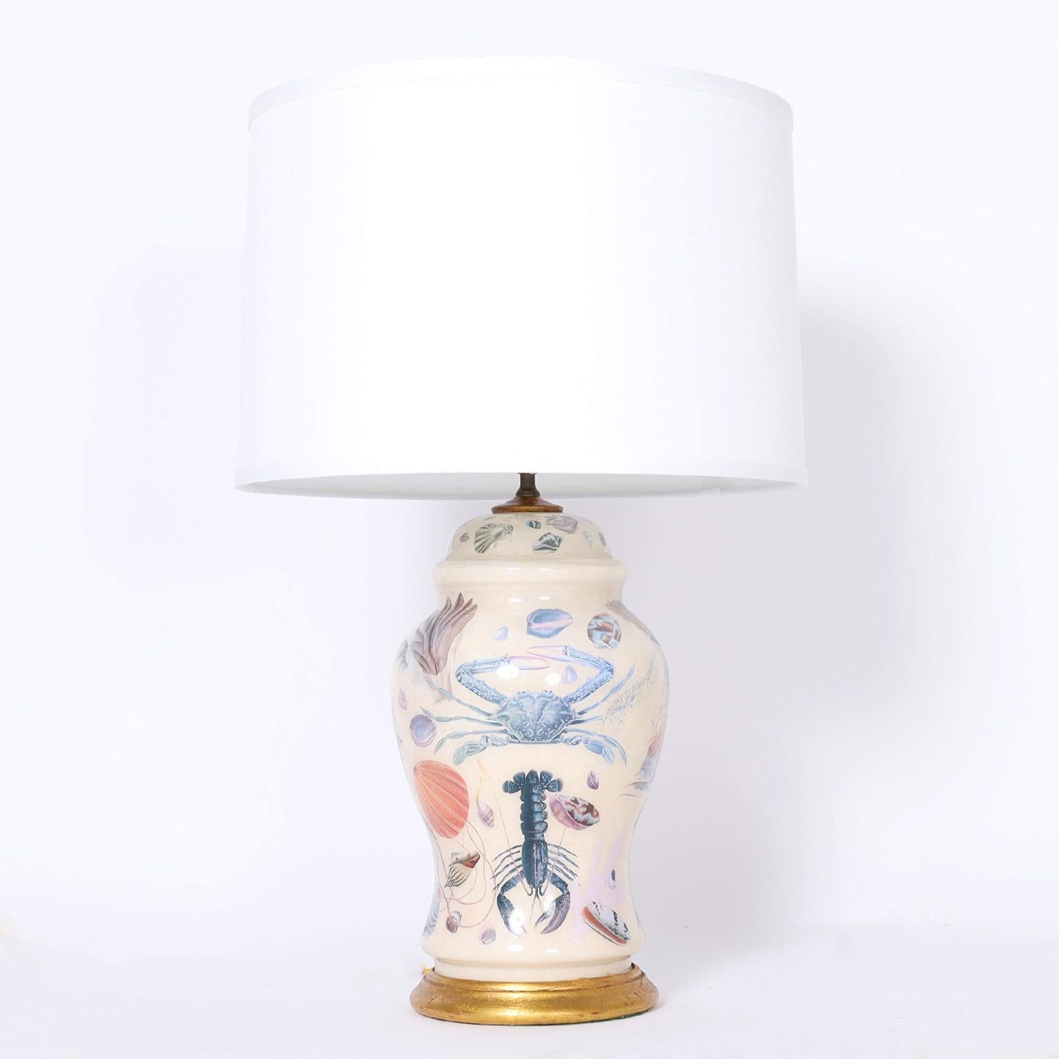 Charming and whimsical pair of table lamps with classic form decorated with a reverse decoupage technique under glass of sea life and shells on a white background. Signed 