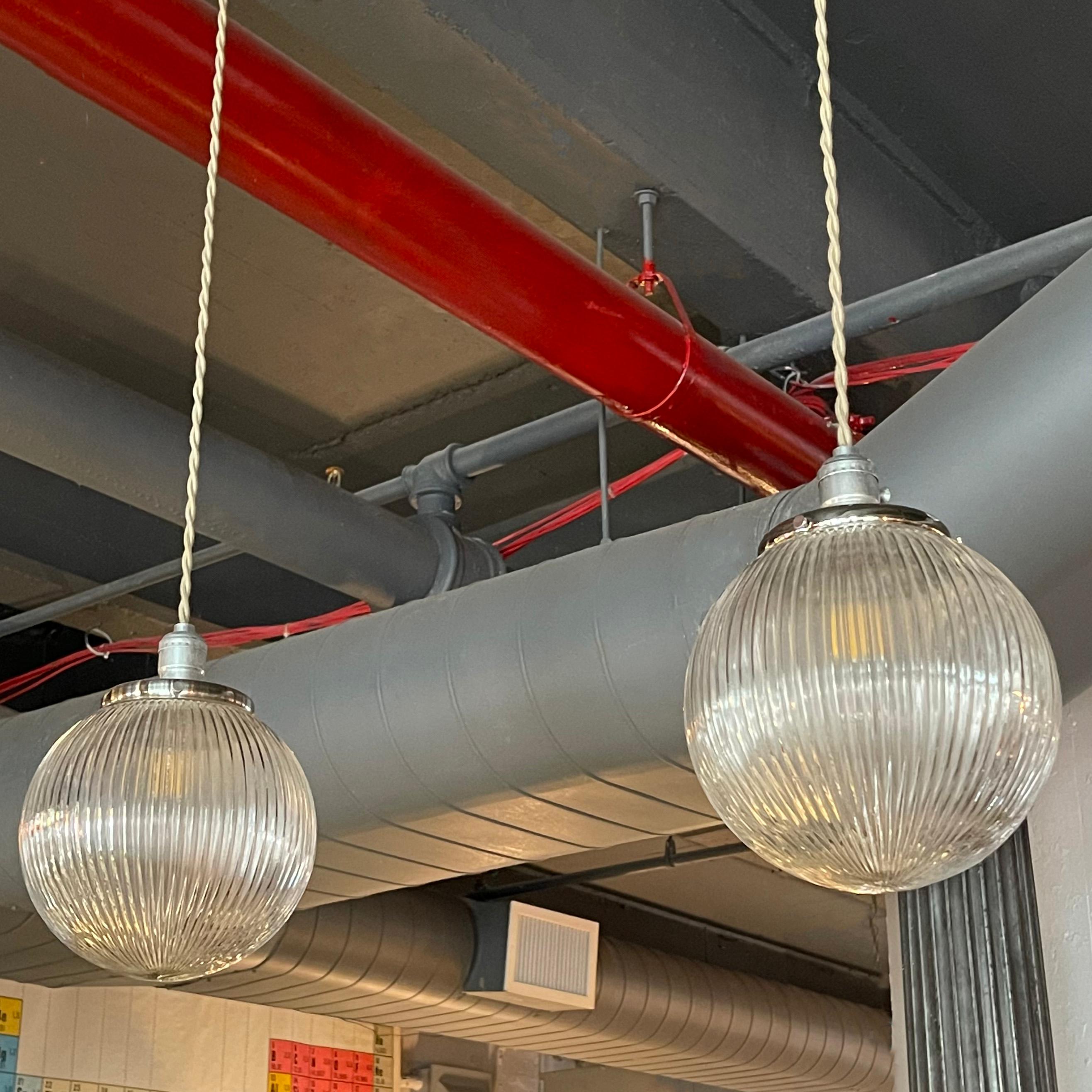 Pair of ribbed glass globe pendants with chrome fitters are newly wired with 48 inches of braided cloth cord.