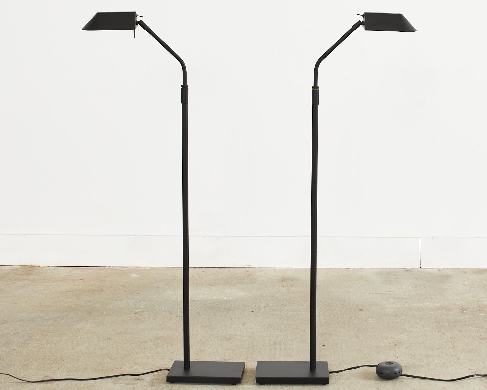 Mid-Century Modern pair of height adjustable pharmacy floor lamps designed by Robert Sonneman for George Kovacs. The lamps have a steel frame with a matte black powder-coated finish. The angled columns adjust from approximately 47 inches high to 53