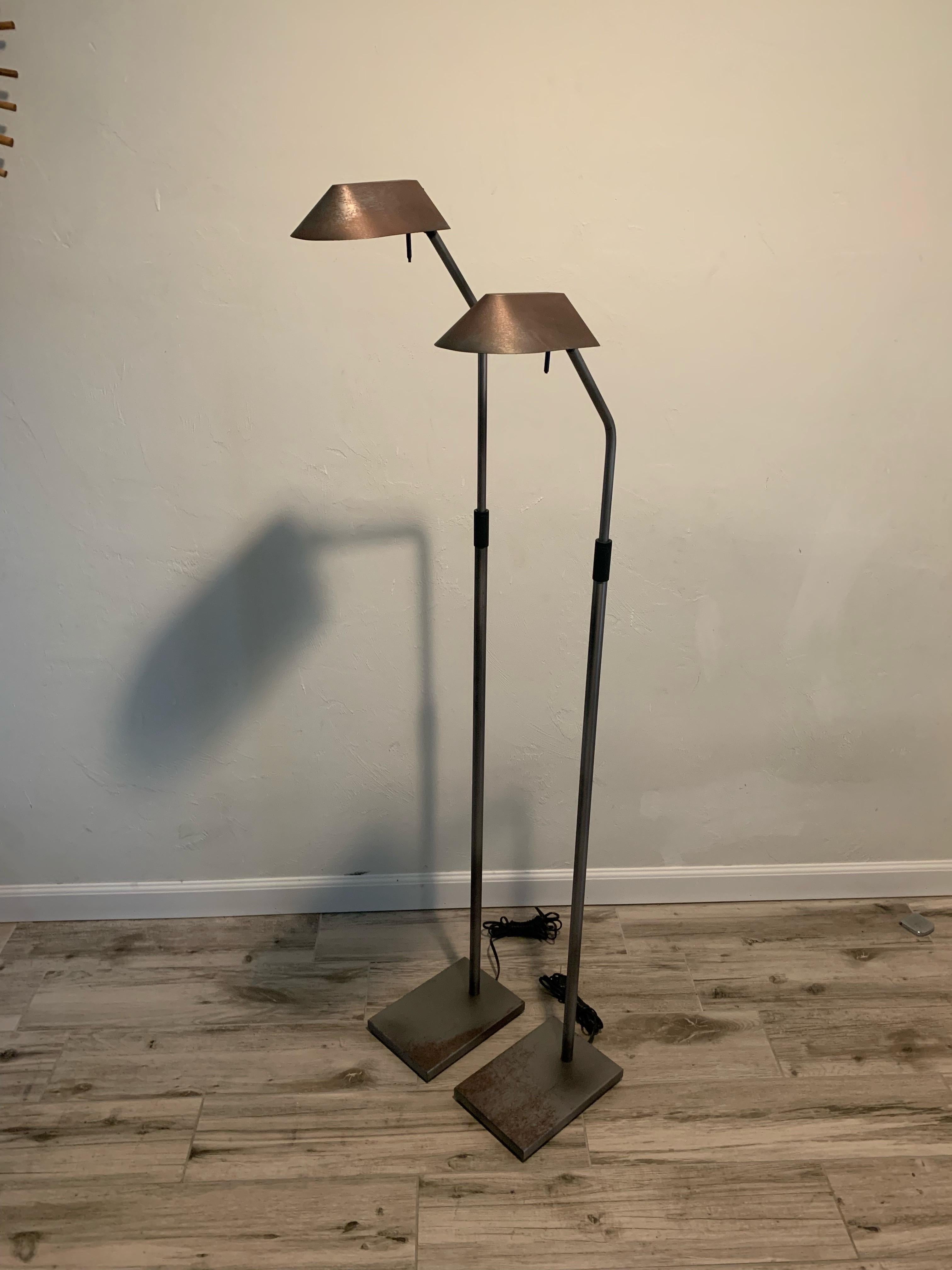 Mid-Century Modern pair of height adjustable pharmacy floor lamps. 

Designed by Robert Sonneman for George Kovacs. 

Lamps have a steel frame. Gunmetal in color and seemingly raw finish. Due to the raw finish there are micro scratches and