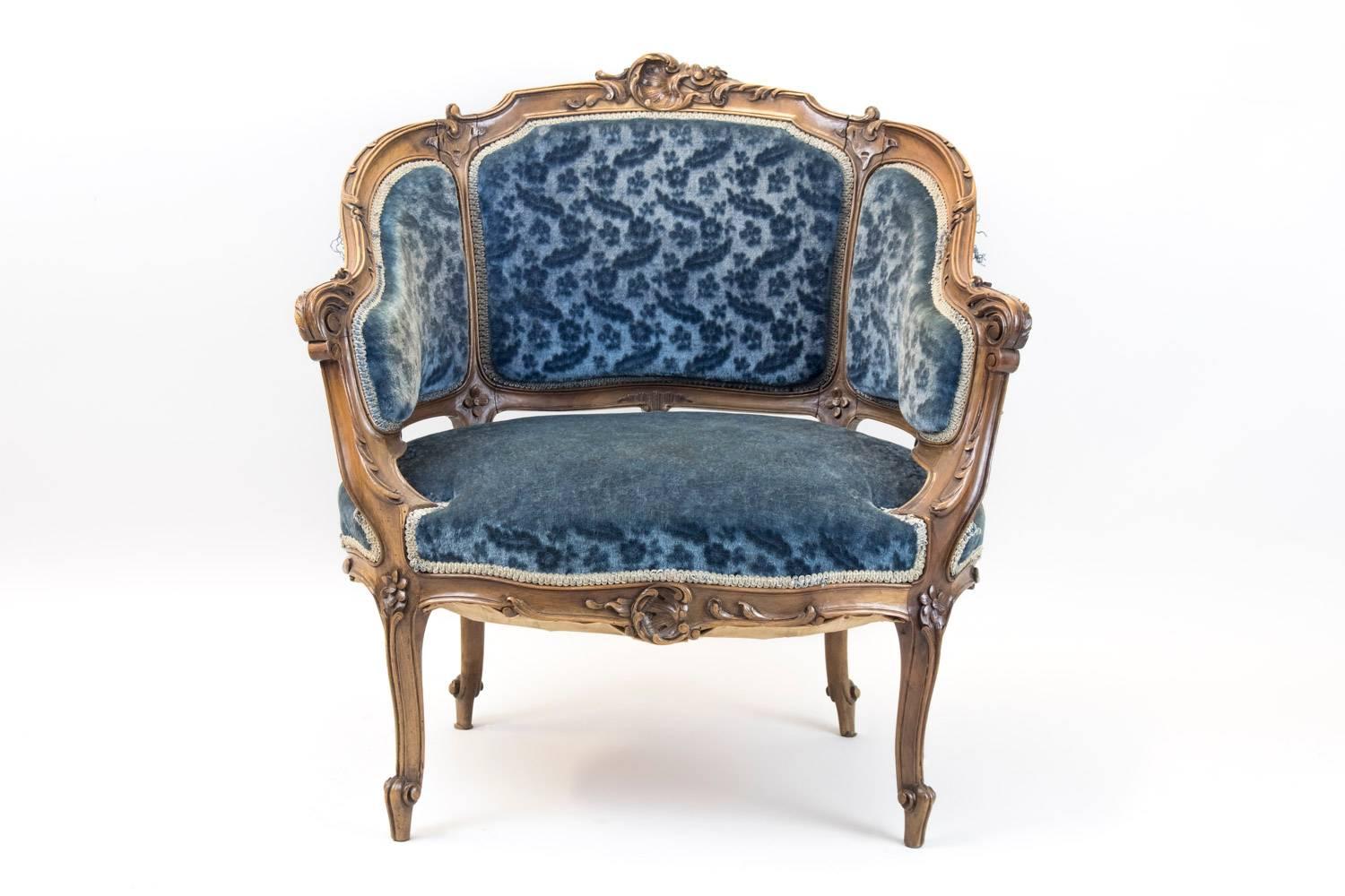 Pair of Rocaille style corbeille-shaped bergere armchairs in carved walnut, standing on four curved legs. Chantournés uprights and apron. Decoration of acanthus leaves on the armrests and of shells, flowers and plants on the apron, uprights and