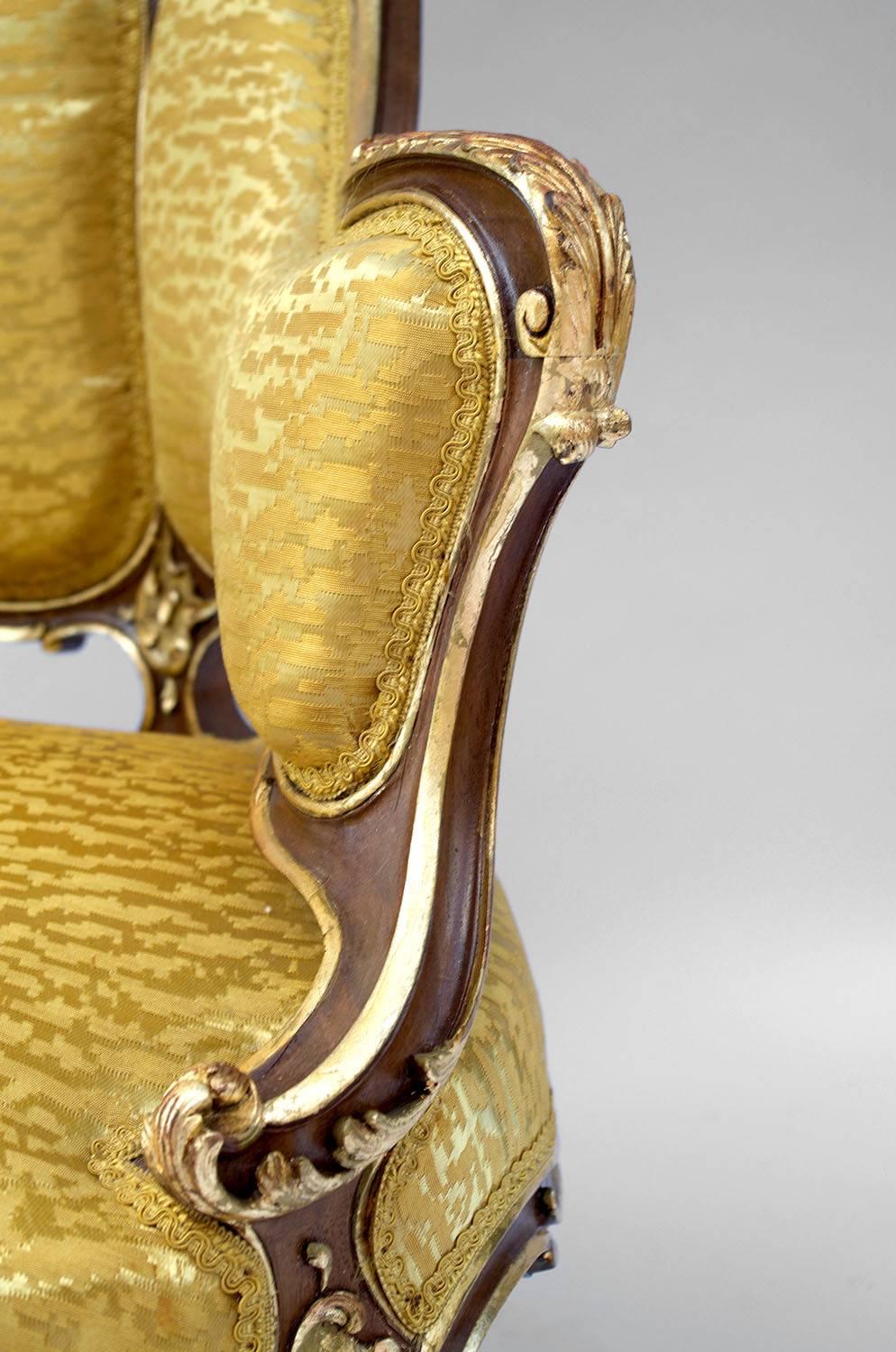 Pair of Rocaille style natural carved walnut with gilt highlights bergère.
Gondole backseat and small curved legs, uprights and armrests in chantourné shape.
Rocaille style carved decorations with gilt highlights as shells, interlaced plants,