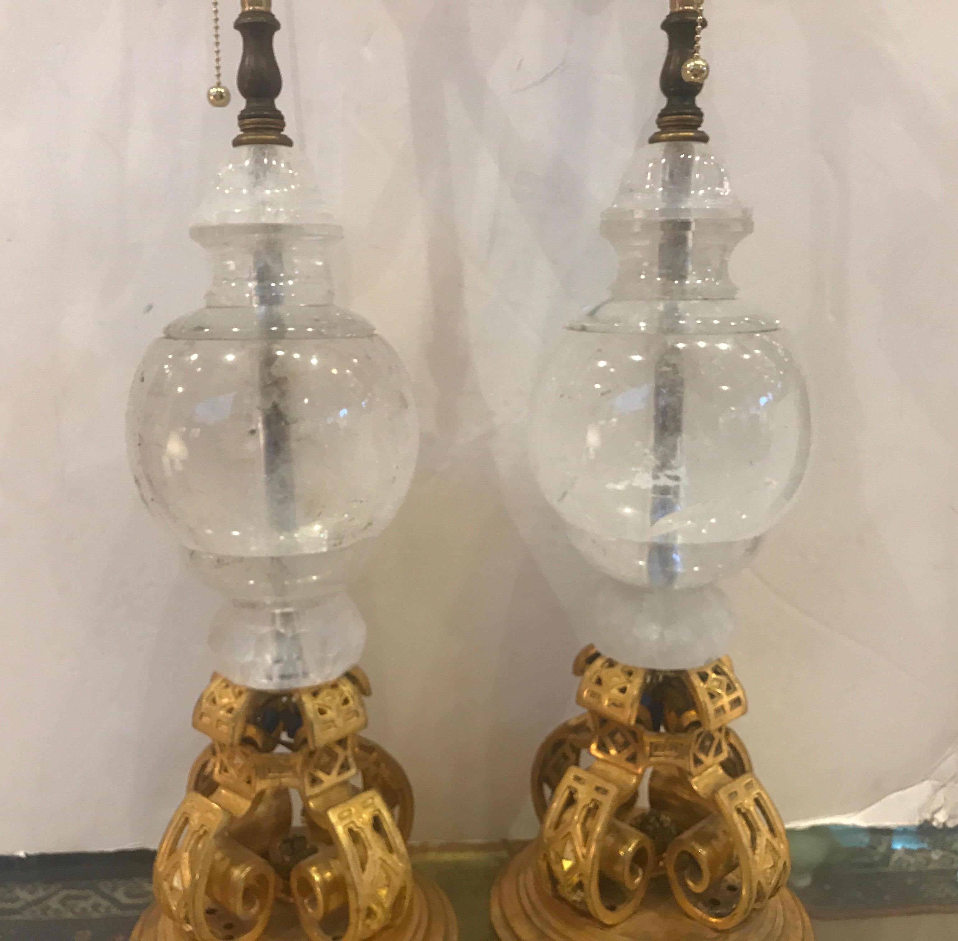 An opulent pair of large rock crystal and gilt bronze lamps. The large solid rock crystal urn with cast gilt bronze bases. The lamps with two light sockets with on/off switch at base. The crystal with some carbon flecks that naturally occur in real
