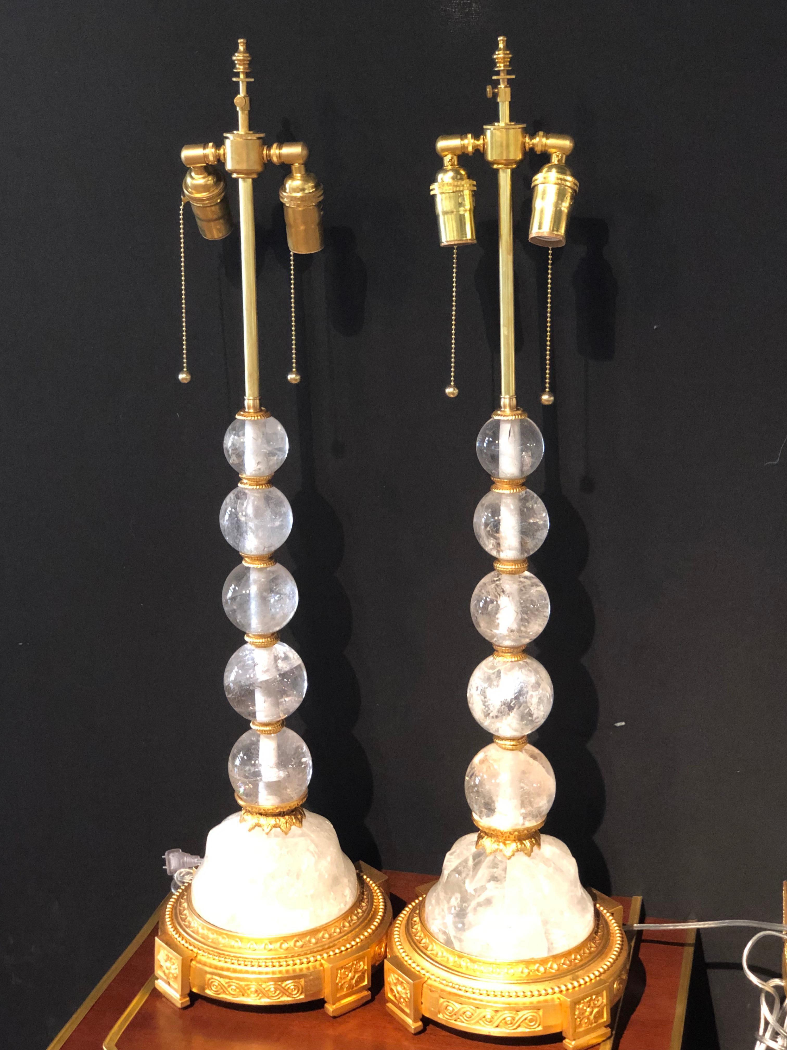A fine pair of rock crystal Hollywood regency or Art Deco style table lamps. The pair having gilt metal supports on a rock form crystal base having a group of graduating rock crystals balls leading to double light sockets with match finials. 
These