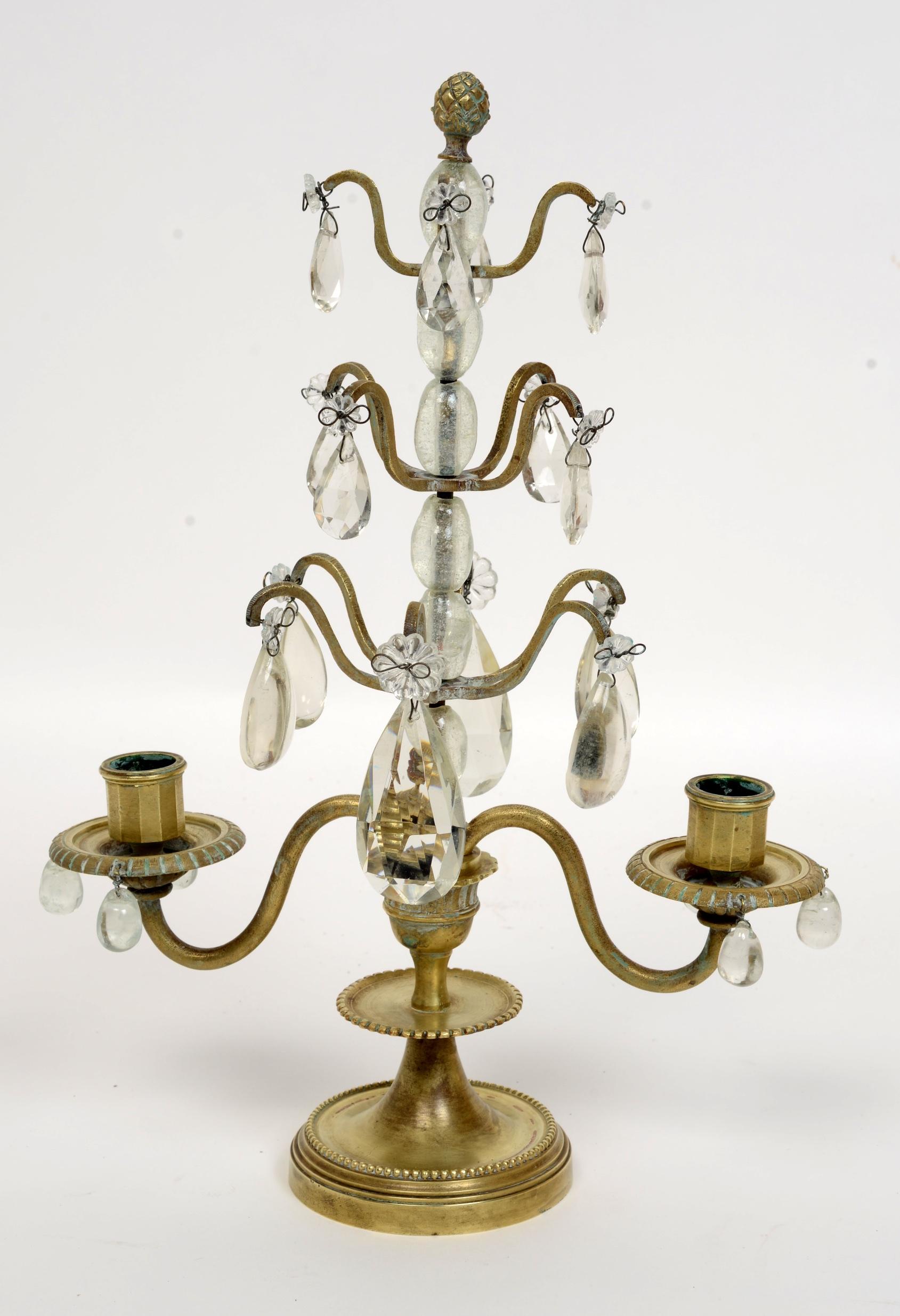 Pair of rock crystal, lead crystal and brass candelabra, late 19th century. This pair of candelabras have a series of large rock crystal beads supporting their stems topped by a pineapple shaped brass finial. From each graduating branch hang crystal