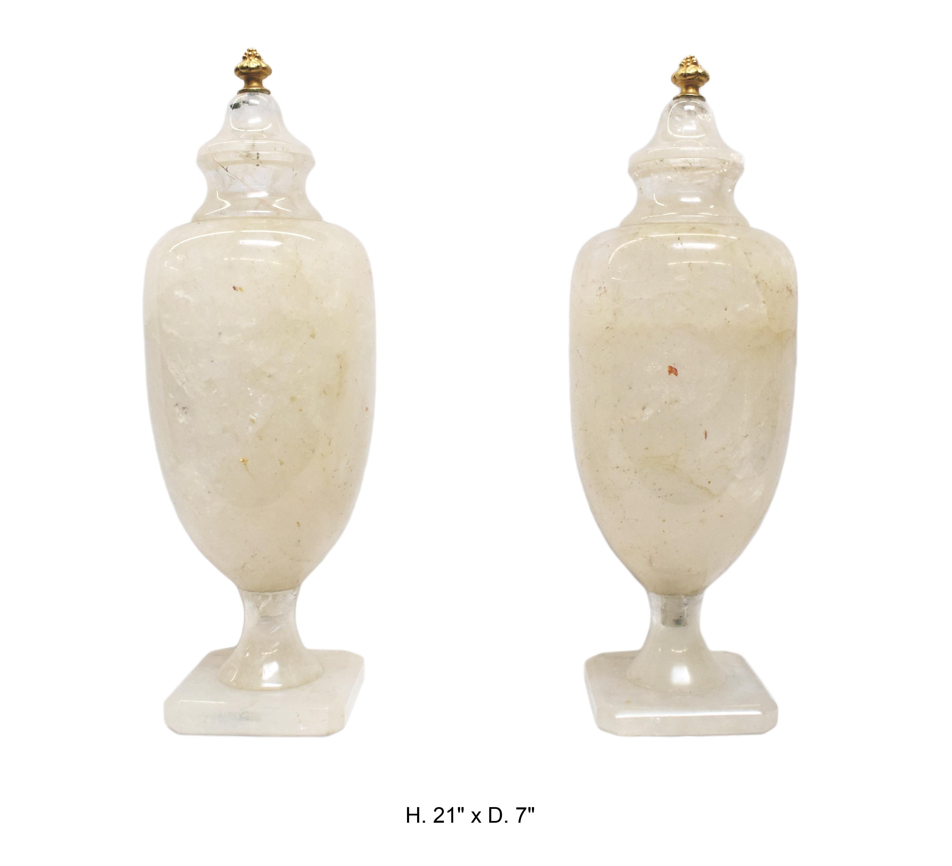 Magnifique paire de vases couverts en cristal de roche de style néo-classique, sculptés et polis à la main. Couronnés de fleurons en forme d'ananas en bronze doré.
La plus grande que nous ayons jamais vue en 40 ans d'activité.
Chaque urne est