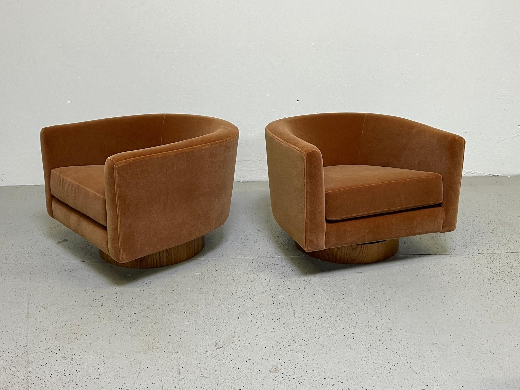 A pair of rocking swivel chairs designed by Milo Baughman for Thayer Coggin. Reupholstered in cinnamon mohair with refinished oak bases.  