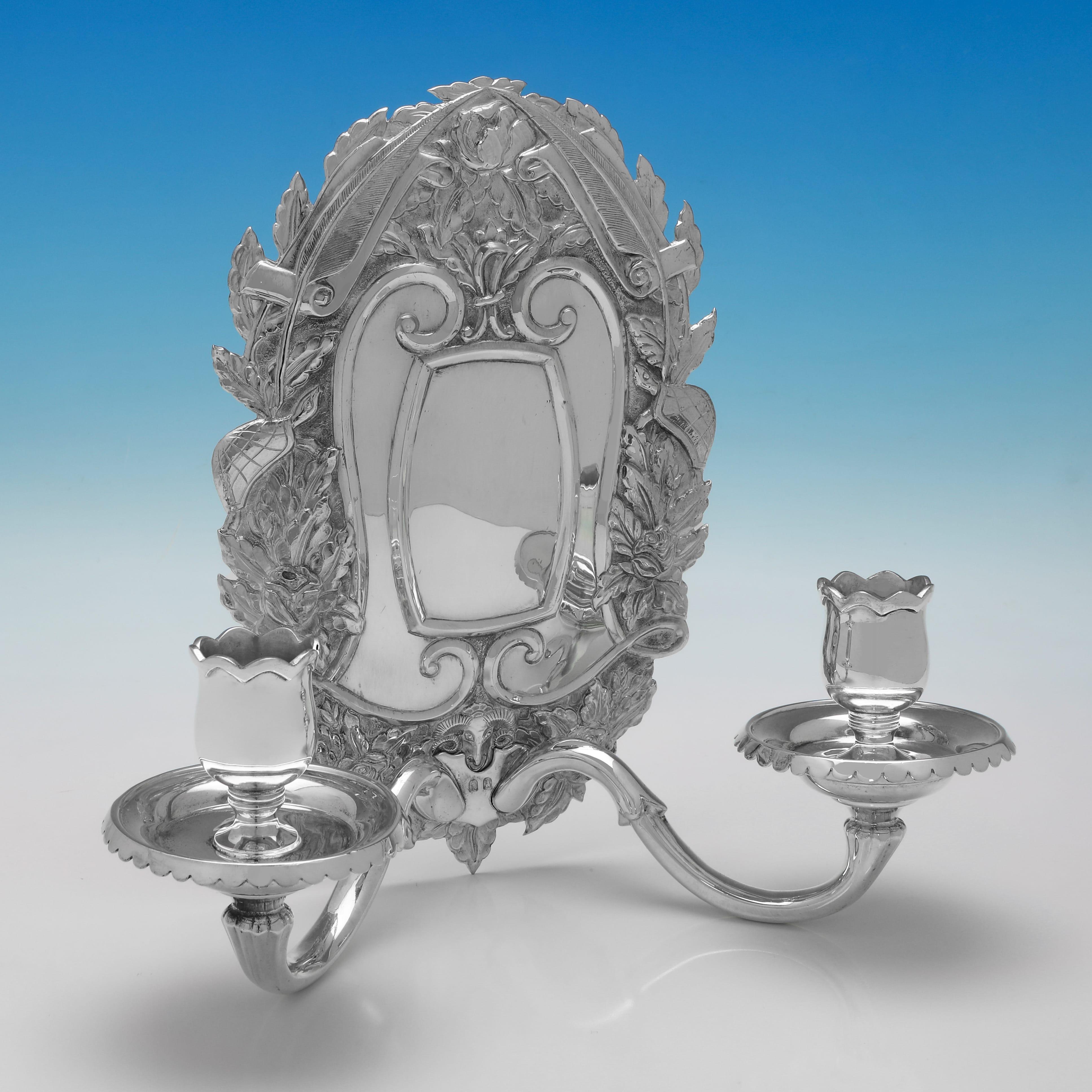 Marchiato a Londra nel 1955 da Asprey & Co. Ltd., questa straordinaria coppia di lampade da parete in argento Britannia Standard, risalenti al periodo di Elisabetta II, sono in stile rococò, molto decorative sul retro e con spazio per 2 candele