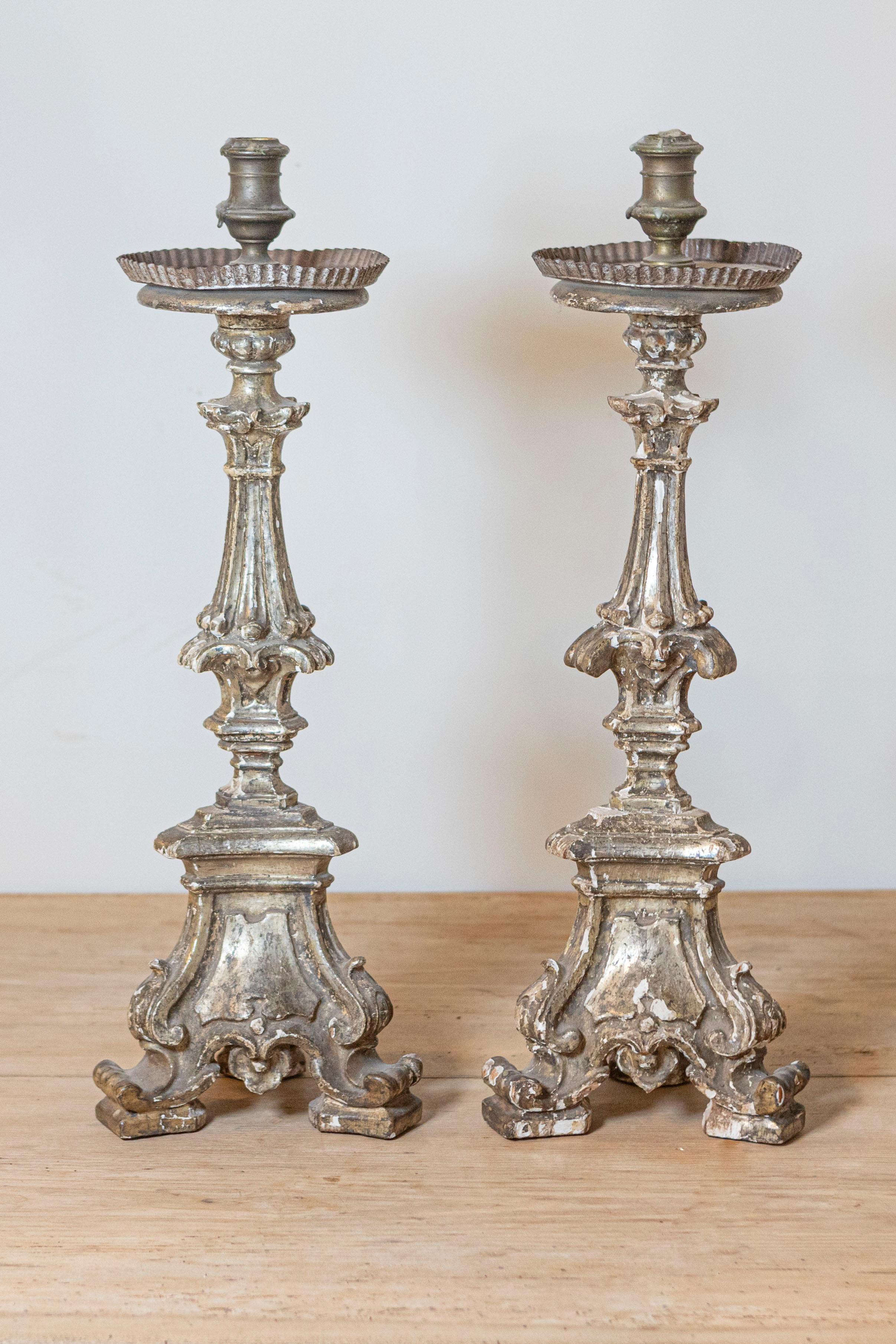 A pair of Italian Rococo period painted candlesticks from the 18th century, with carved cartouches and scrolling feet. Created in Italy during the 18th century, each of this pair of Rococo candlesticks features a carved column resting on a tripod